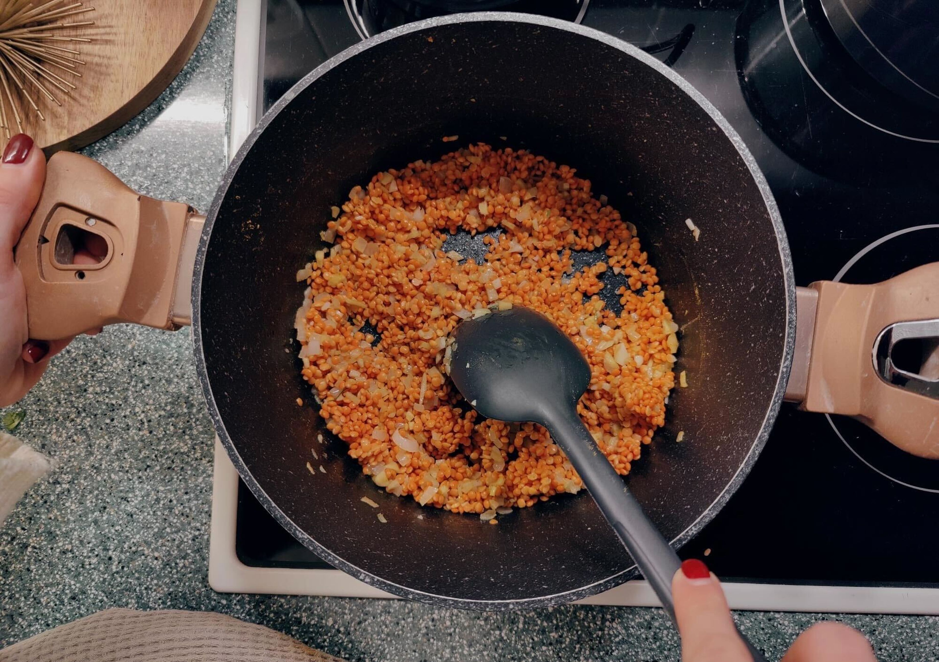Öl in eine Pfanne geben und Zwiebeln bei mittlerer Hitze glasig dünsten. Dann Curry, Knoblauch, Chiliflocken und Ingwer hinzufügen und ca. 2 Min. anbraten. Linsen zufügen und ebenfalls kurz mitbraten.