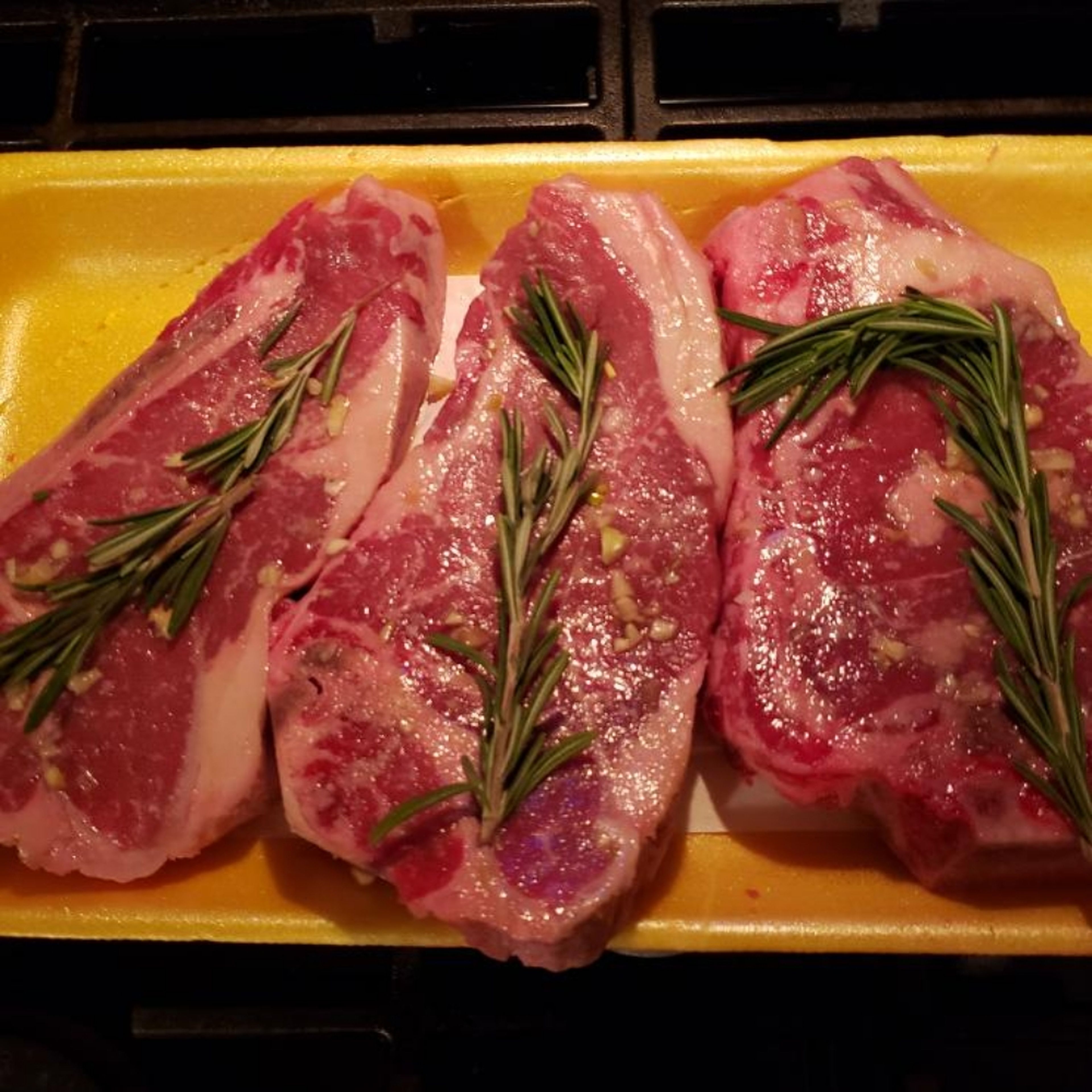 Mince garlic and fresh rosemary. Coat steaks in a thin coat of olive oil. Season with salt and pepper to taste. Spread some of the minced garlic and rosemary on both sides. Place mushrooms on foil, coat in olive oil, salt, pepper and garlic and rosemary. Wash Shishitos and coat in olive oil and garlic.