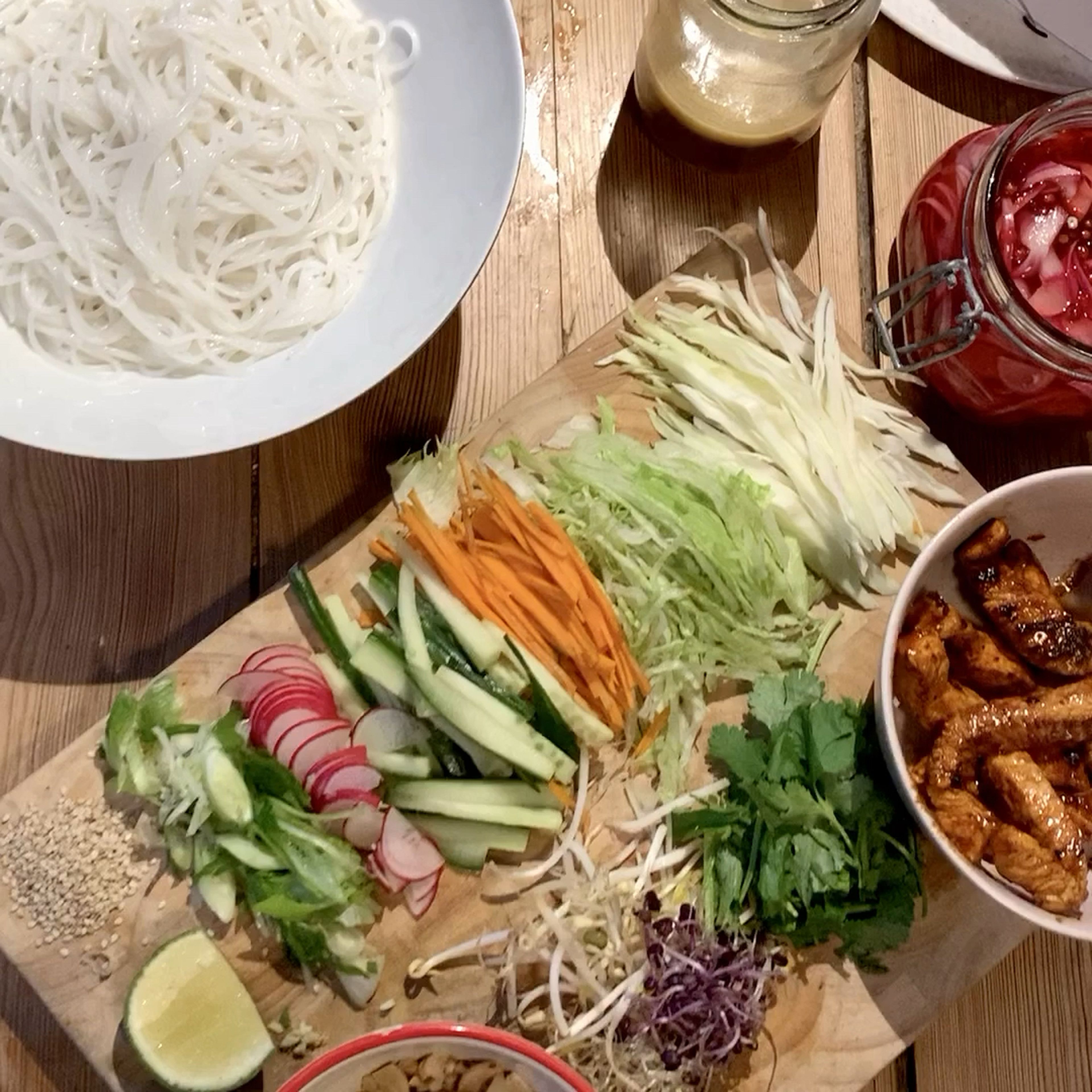 Die Reisnudeln mit allen Zutaten in einer Schüssel anrichten. Mit den Kräutern und Erdnüssen garnieren und mit frischer Limette servieren. Guten Appetit!