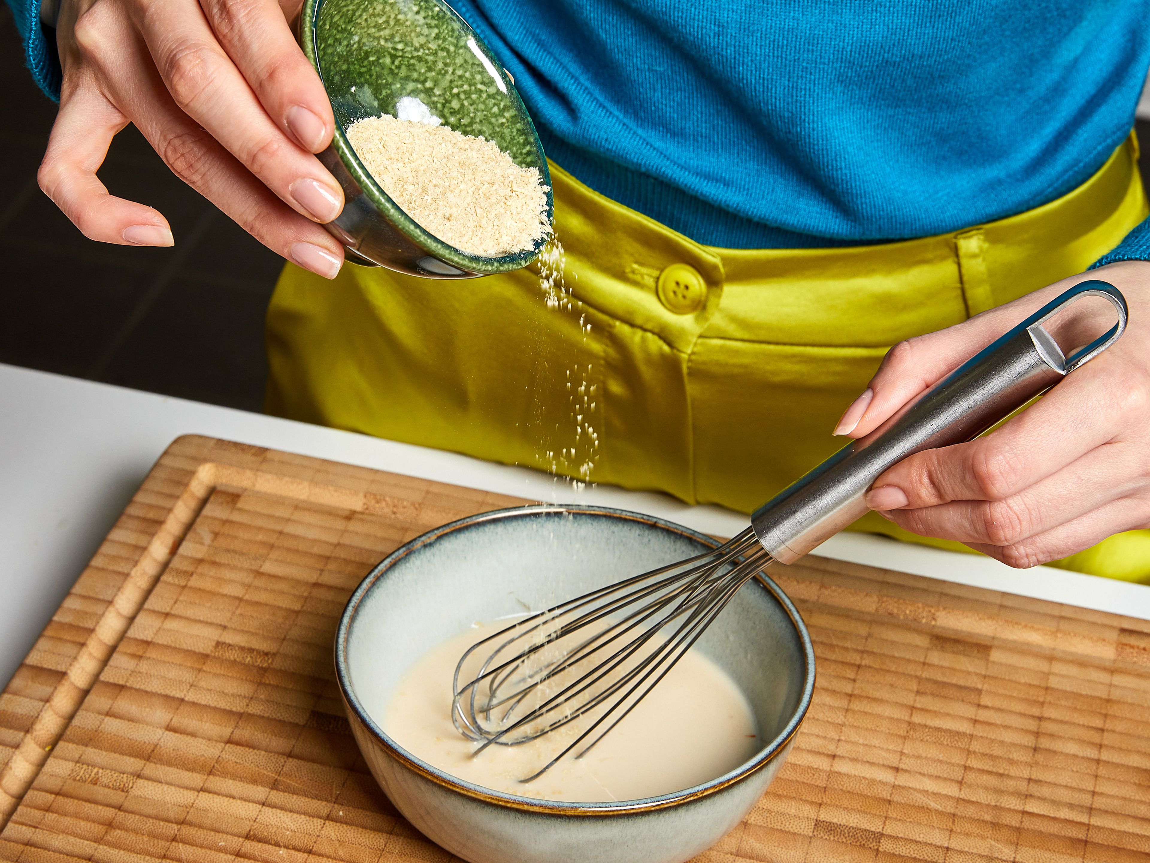 Während die Zwiebeln karamellisieren, den Knoblauch fein hacken. Die Zitrone abreiben und auspressen. In einer kleinen Schüssel den Zitronensaft mit der pflanzlichen Milch und den Hefeflocken vermischen, gut verrühren und beiseitestellen.
