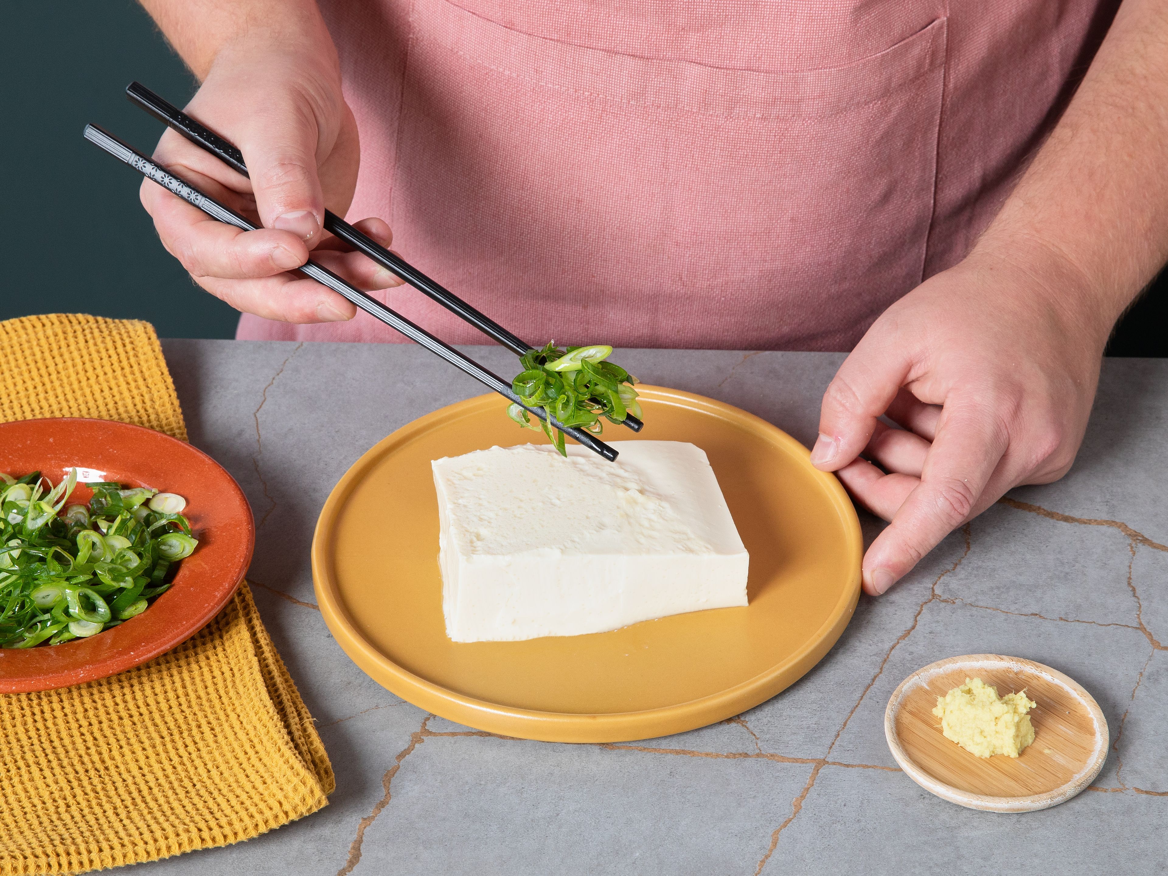 Den Seidentofu auf einen kleinen Teller oder Schälchen geben. Den geriebenen Ingwer und die Frühlingszwiebeln darauf verteilen. Ponzu-Sauce und Sesamöl in einem kleinen Schälchen vermischen.