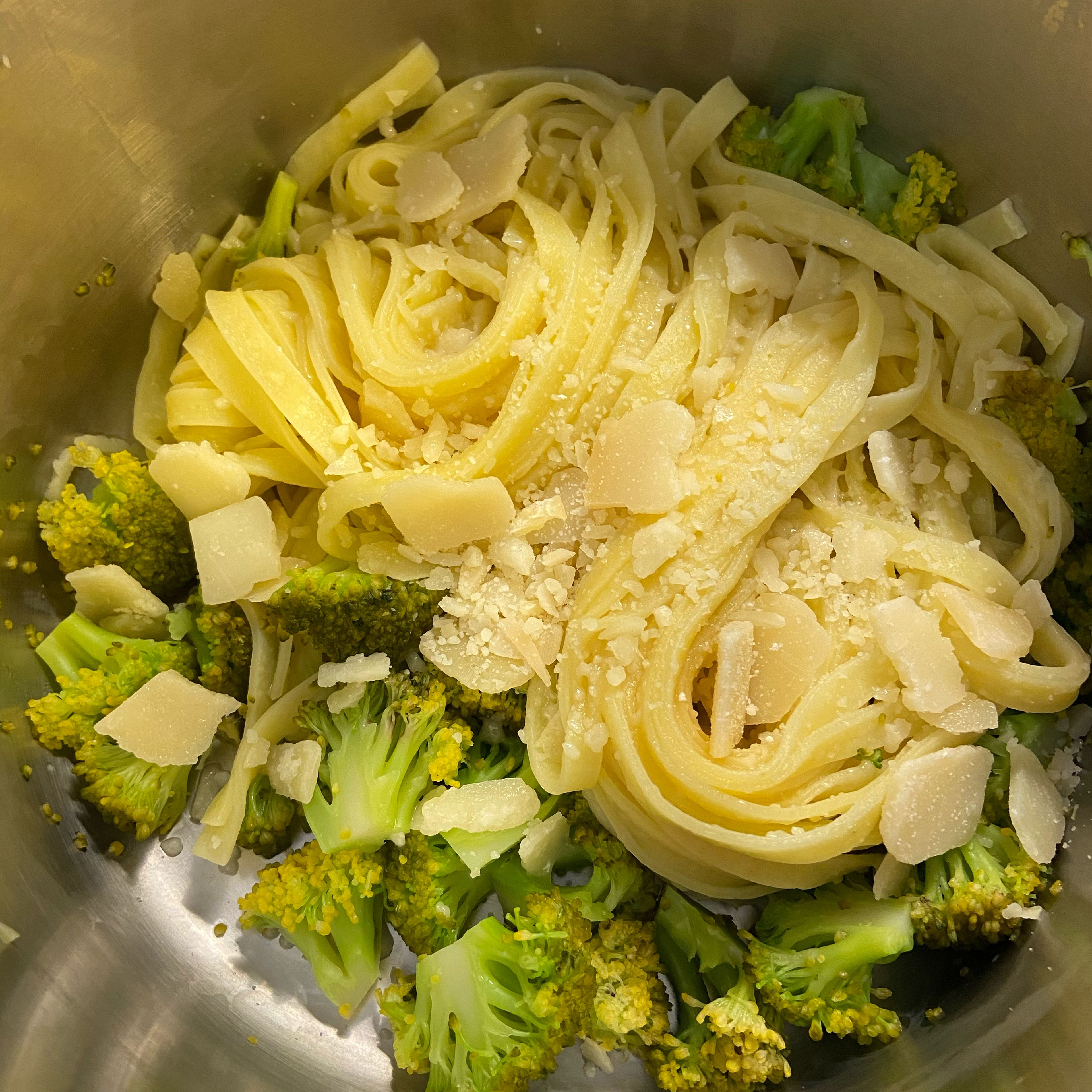 Pasta und Brokkoli abgießen und erneut in den Topf geben. Darüber die Hälfte vom grob geriebenen Parmesan streuen.