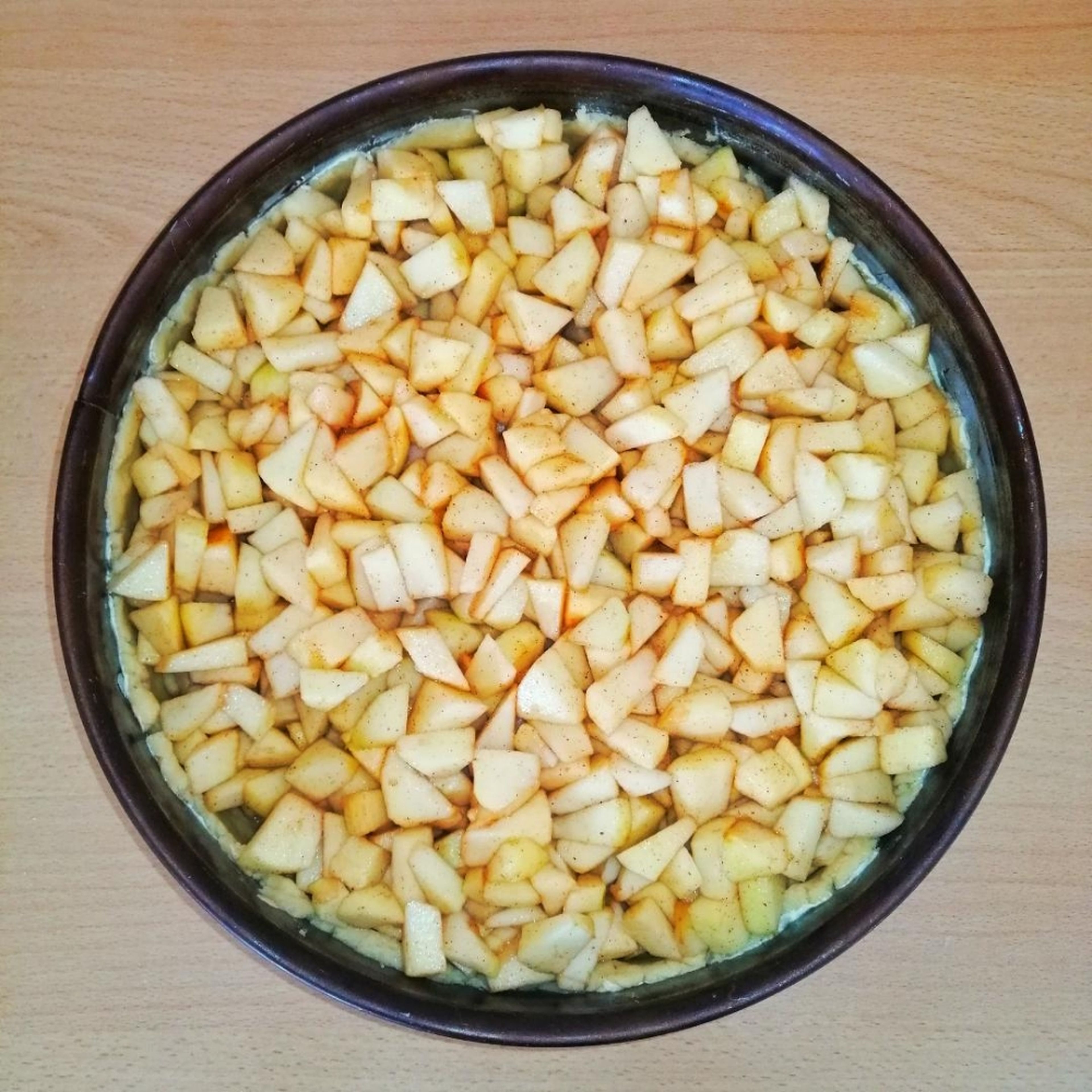 Die Apfelstückchen jetzt in die Kuchenform mit dem Teig geben. Die Form kann man dabei ein paar Mal auf die Arbeitsfläche klopfen. Dabei verteilen sich die Äpfel wie von selbst recht gerade in der Form.