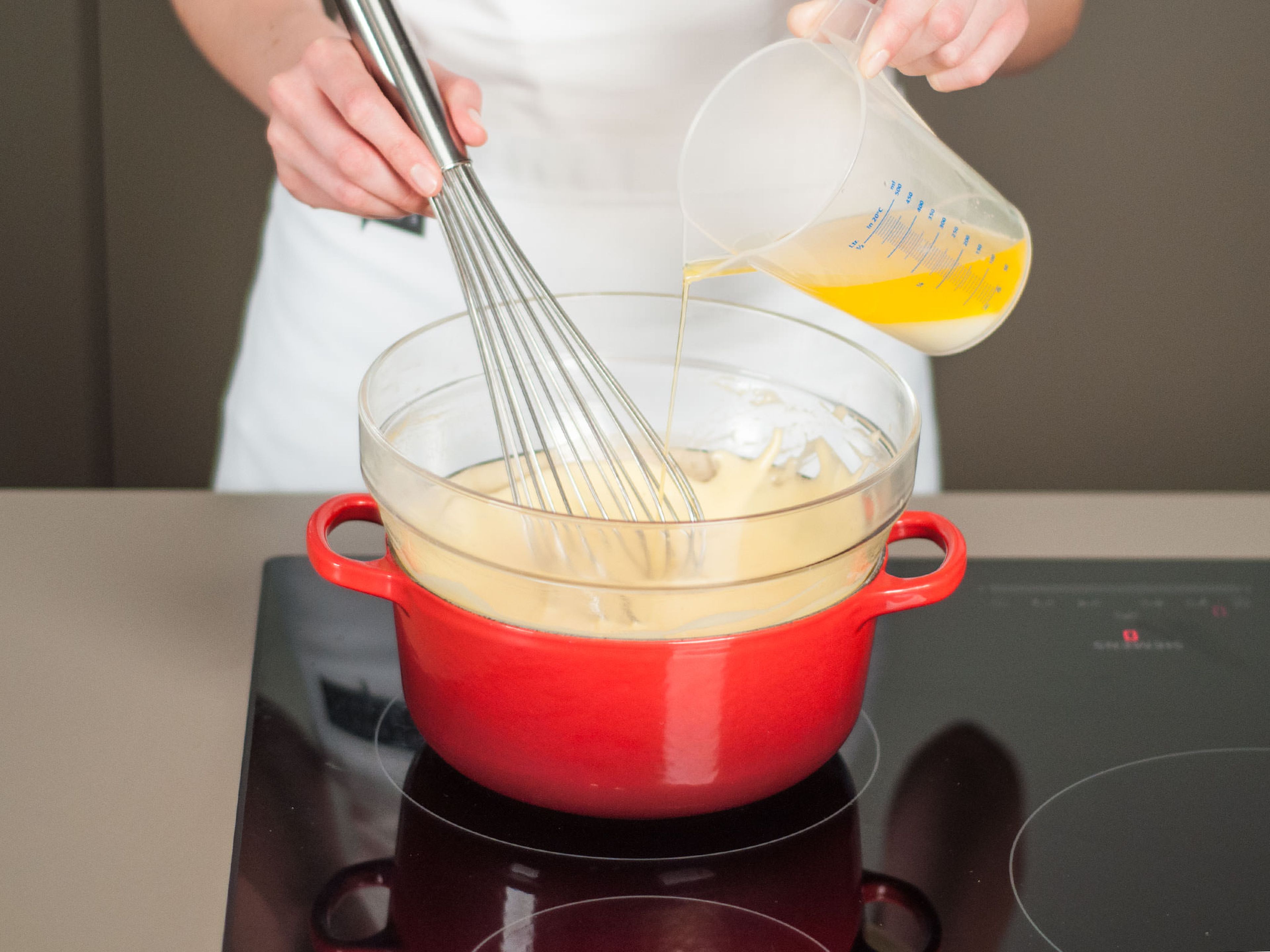 In einem langsamen und gleichmäßigen Strahl die geschmolzene Butter zum Eigelb gießen und rühren, bis die Soße eindickt und sich verdoppelt hat.
