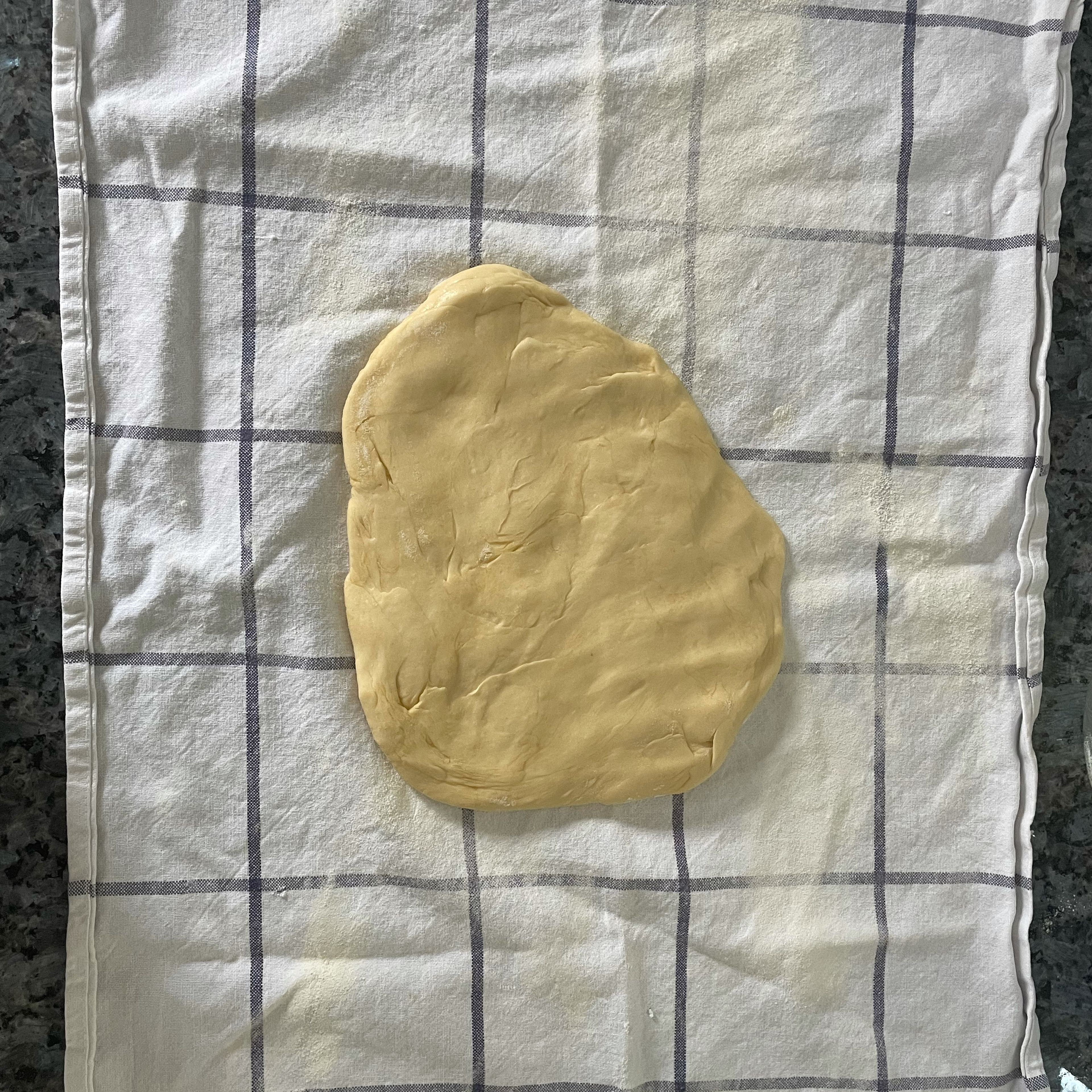 Nun den Teig in Mehl wenden und auf einem großzügig bemehlten Geschirrtuch oder Strudeltuch rechteckig auswellen. Den Teig so dünn wie möglich mit den Handrücken ausziehen