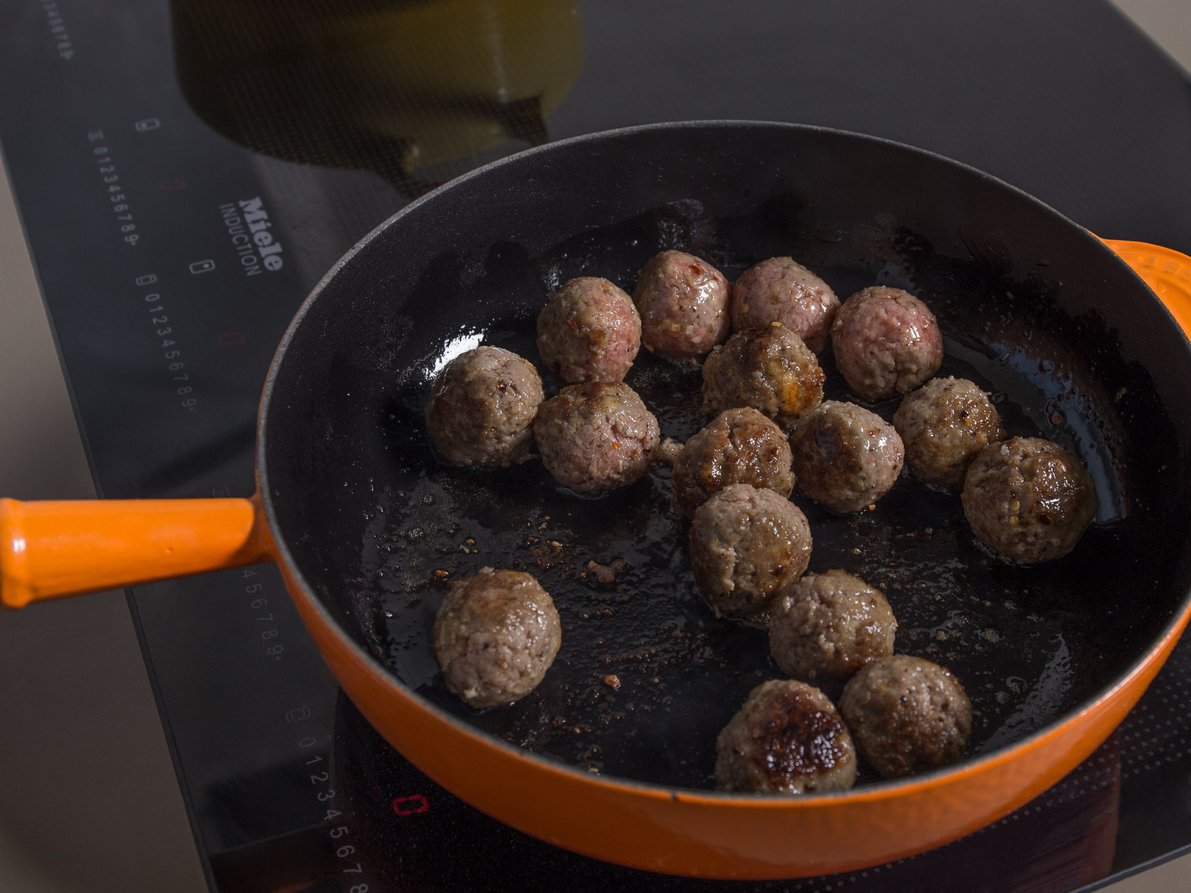 While the meatballs are resting, chop remaining shallots and garlic and sauté in a saucepan with some of the olive oil. Add the crushed tomatoes, season with salt and pepper, and let it simmer. Heat remaining olive oil in the other large frying pan and fry meatballs on all sides for approx. 5 min., or until browned on all sides. Remove from heat and transfer to the tomato sauce. Let simmer for approx. 15 – 20 min.