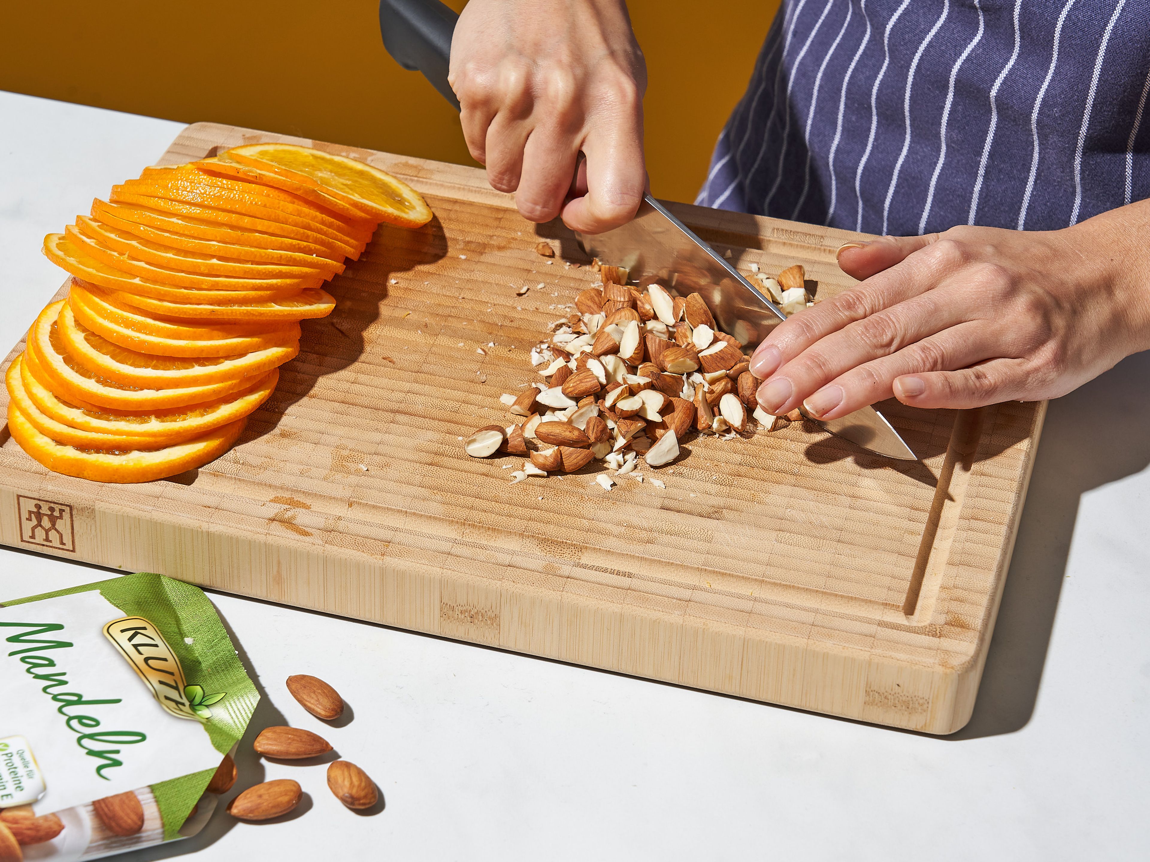 Preheat the oven to 200°C/400°F. Coat the bottom and sides of a springform pan with oil. Line the bottom of the pan with parchment paper and coat with more oil. Chop the almonds. Use a knife to slice the top and tail off of the oranges, then use a mandoline to very thinly slice the fruit (approx. 0,3 cm/ ⅛ in.). Remove and discard any seeds from the slices.