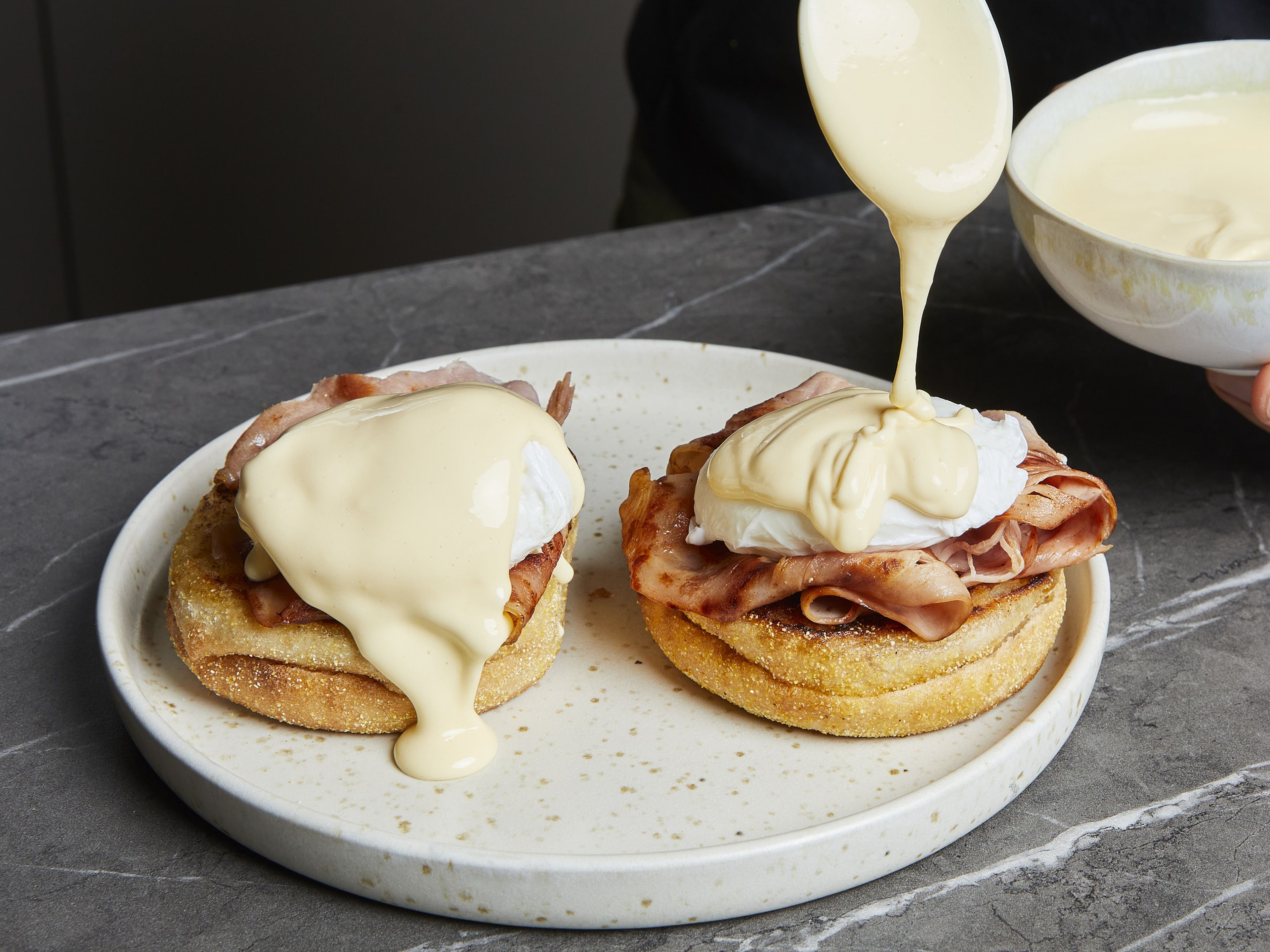 To assemble your Eggs Benedict, place a slice of cooked ham on each English muffin half, top with a poached egg and cover with hollandaise sauce. Season with salt and pepper and garnish with chives if desired.