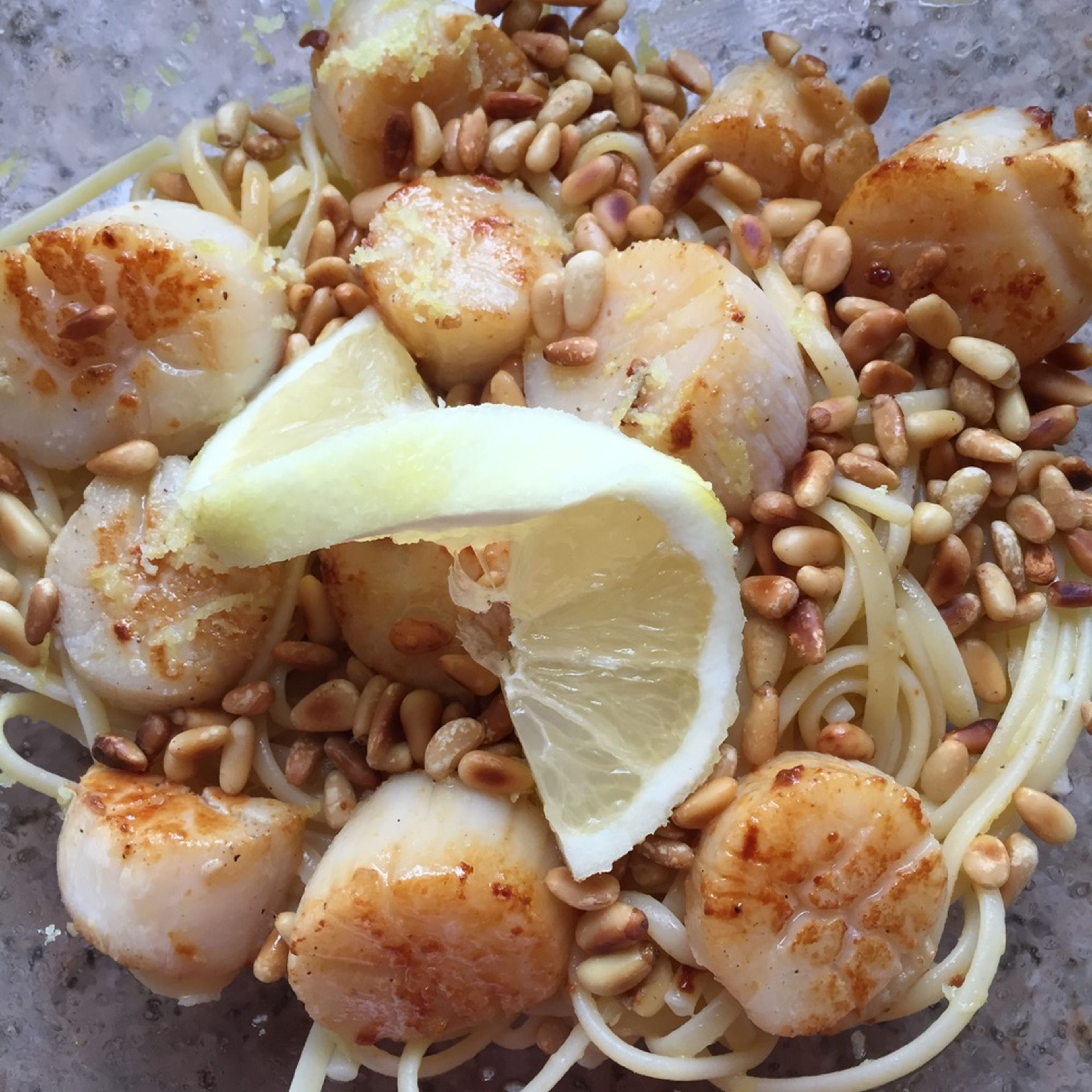 Mix the hot pasta with the with lemon-oil mixture. Serve with pine nuts, basil, and scallops. Enjoy!