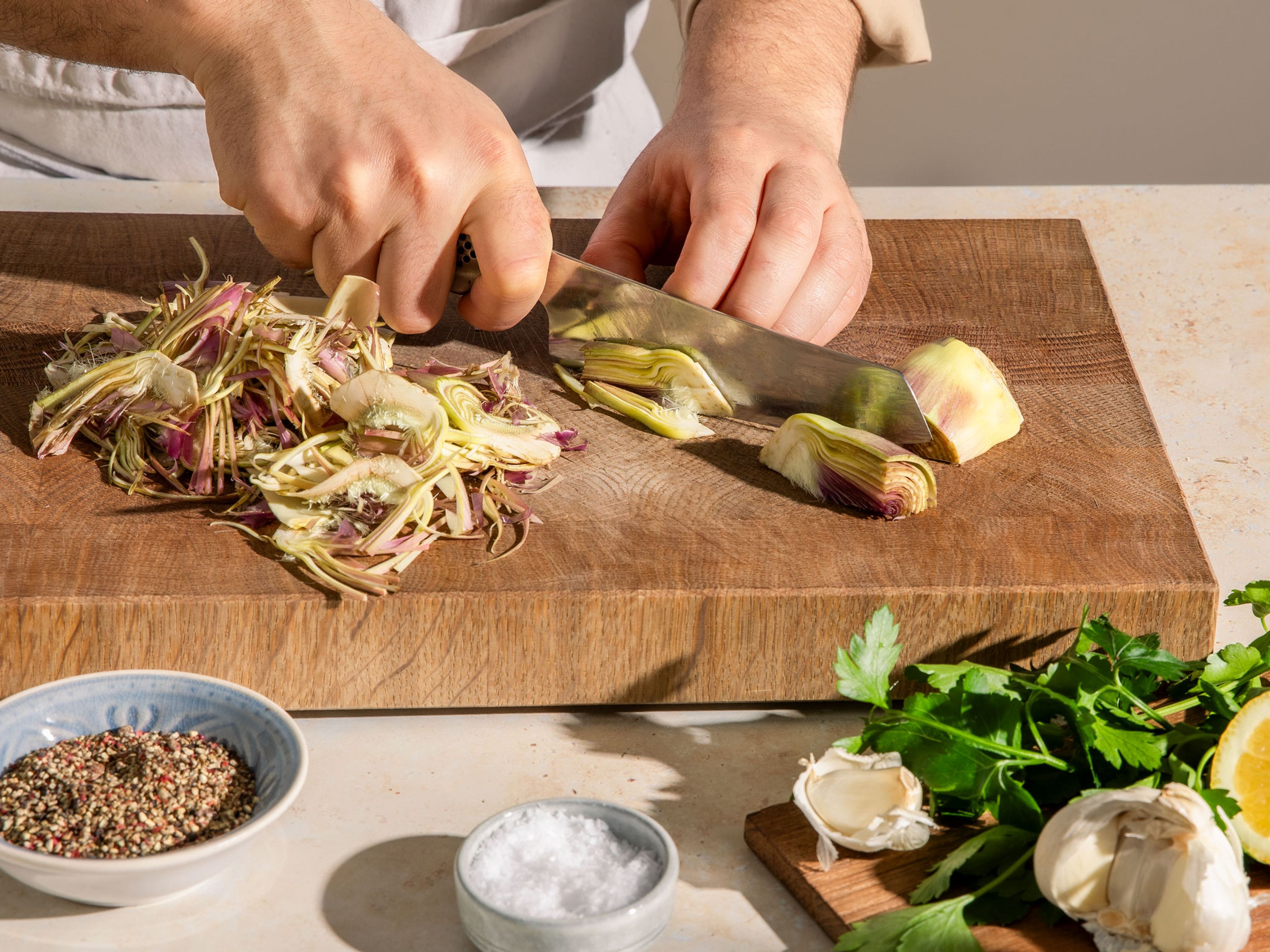 Quarter the artichokes. Then use a mandoline or a sharp knife to cut them sideways into approx. 2–3 mm thin slices so that the original shape remains visible.