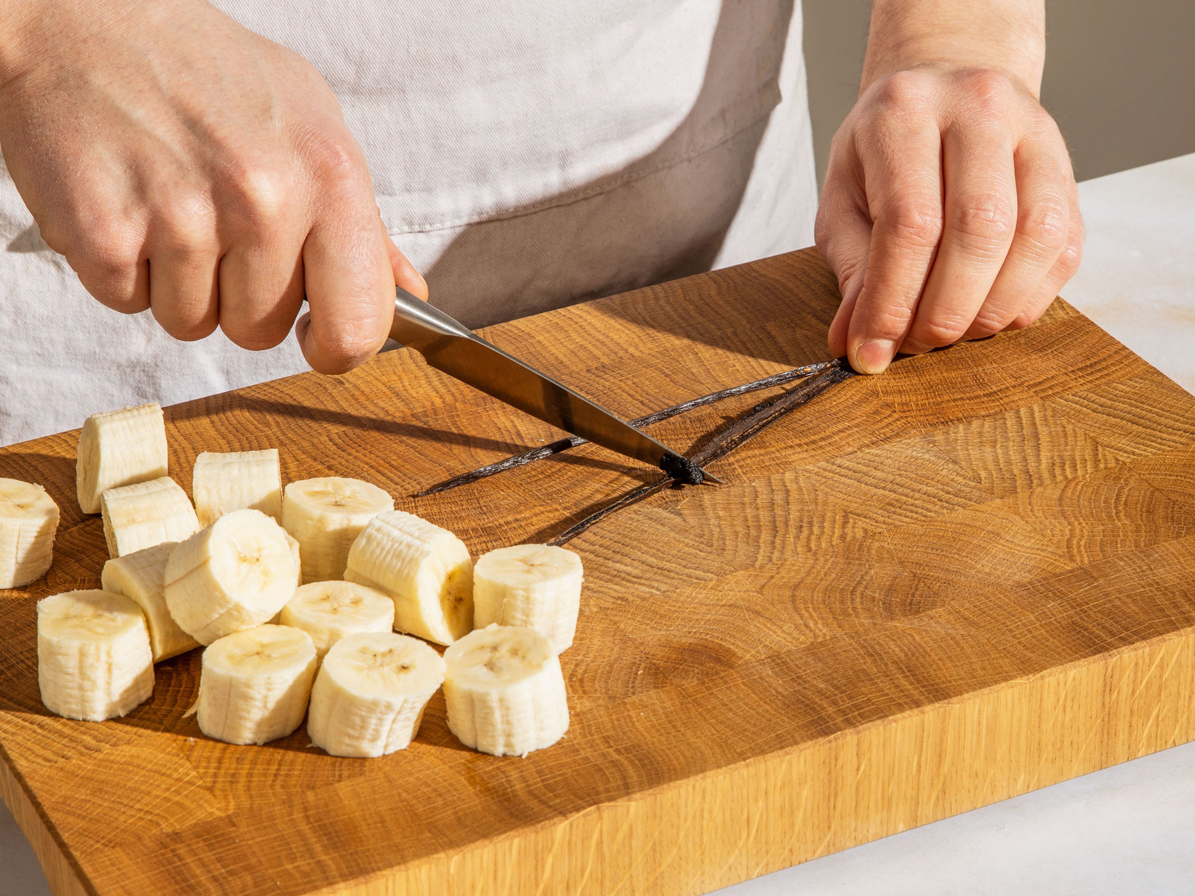 Die Bananen schälen und in kleinere Stücke schneiden. Die Vanilleschote der Länge nach aufschneiden und mit der flachen Seite eines Messers das Vanillemark herauskratzen.
