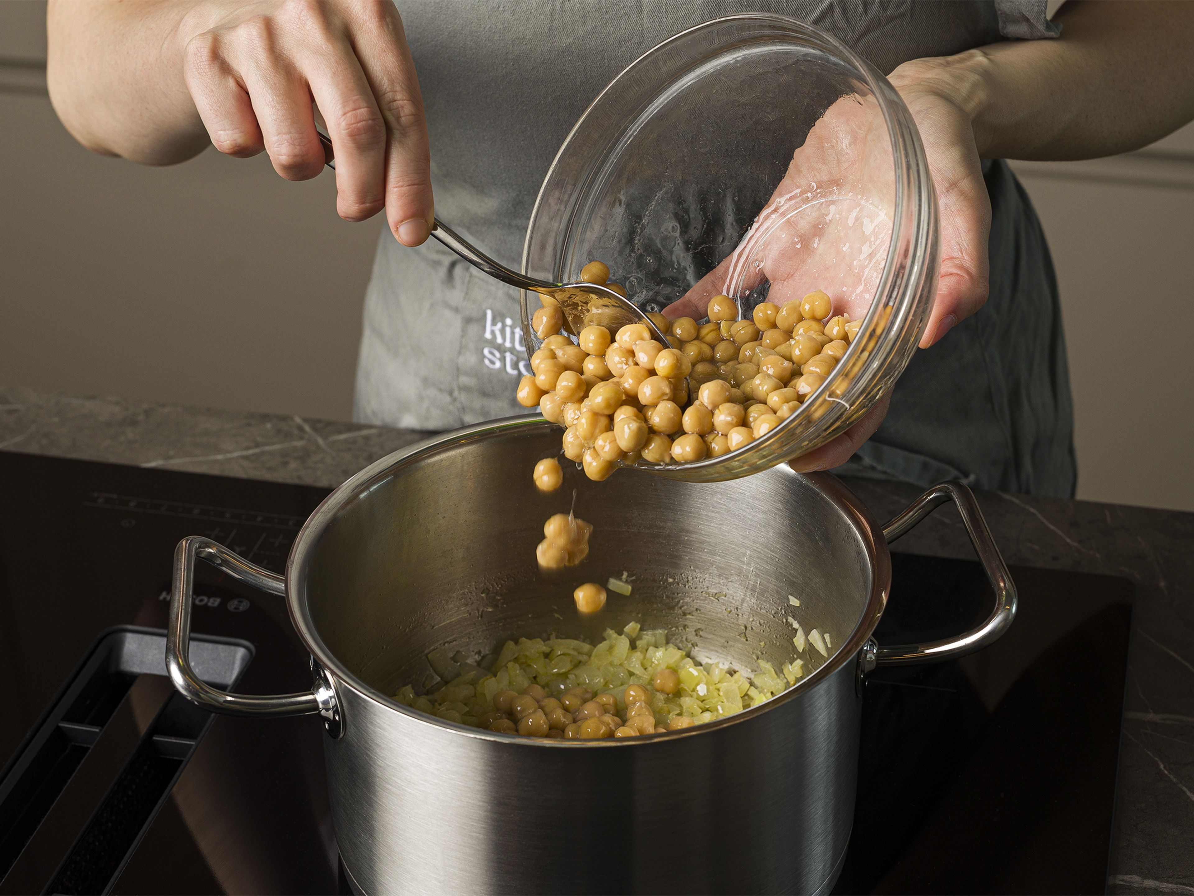 Heat olive oil in a pot over medium-high heat. Add onion and garlic, fry for approx. 2 min. Add chickpeas, vegetable broth, and half of the feta cheese, and cook for approx. 10 min. Season with salt and pepper.