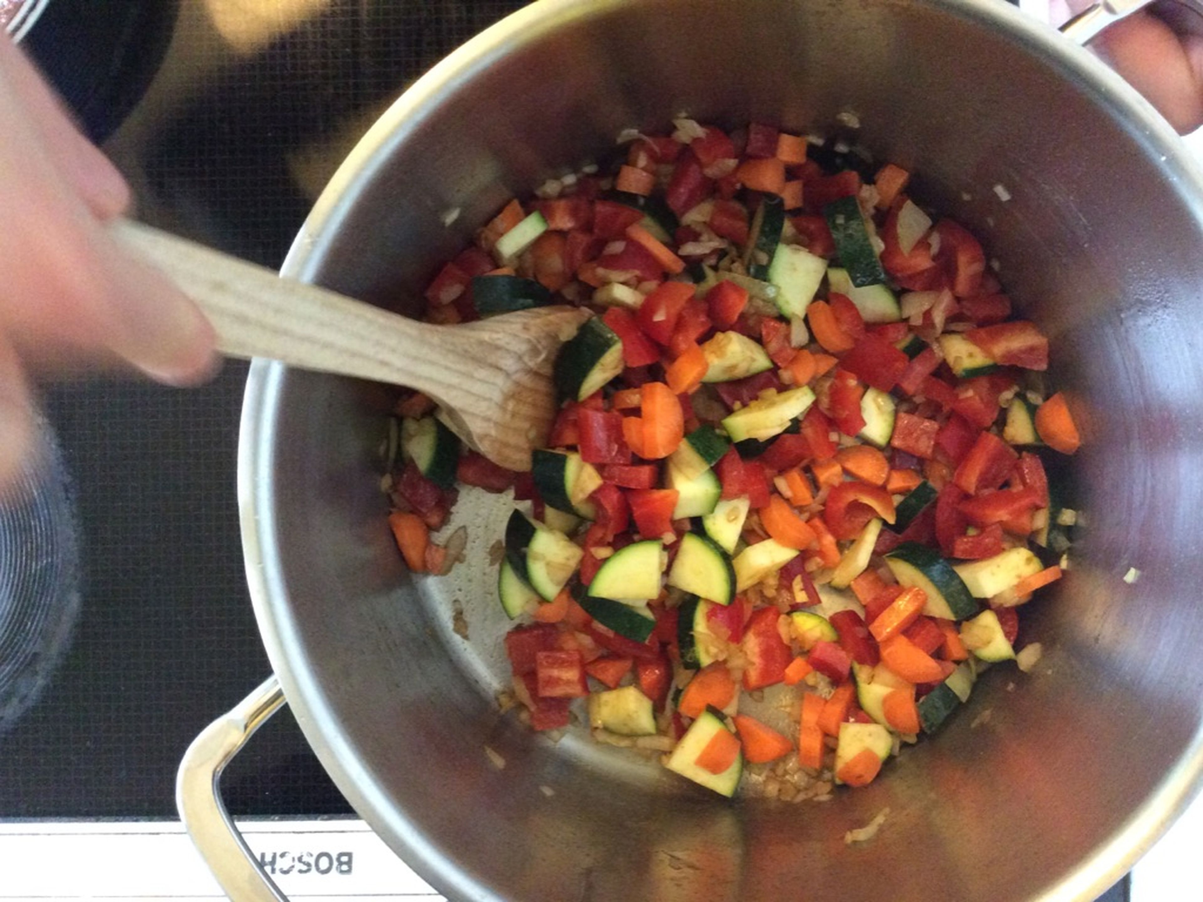 Zucchini, Karotten und Paprika hinzugeben und kurz mit anbraten. Nun die Tomaten dazugeben.