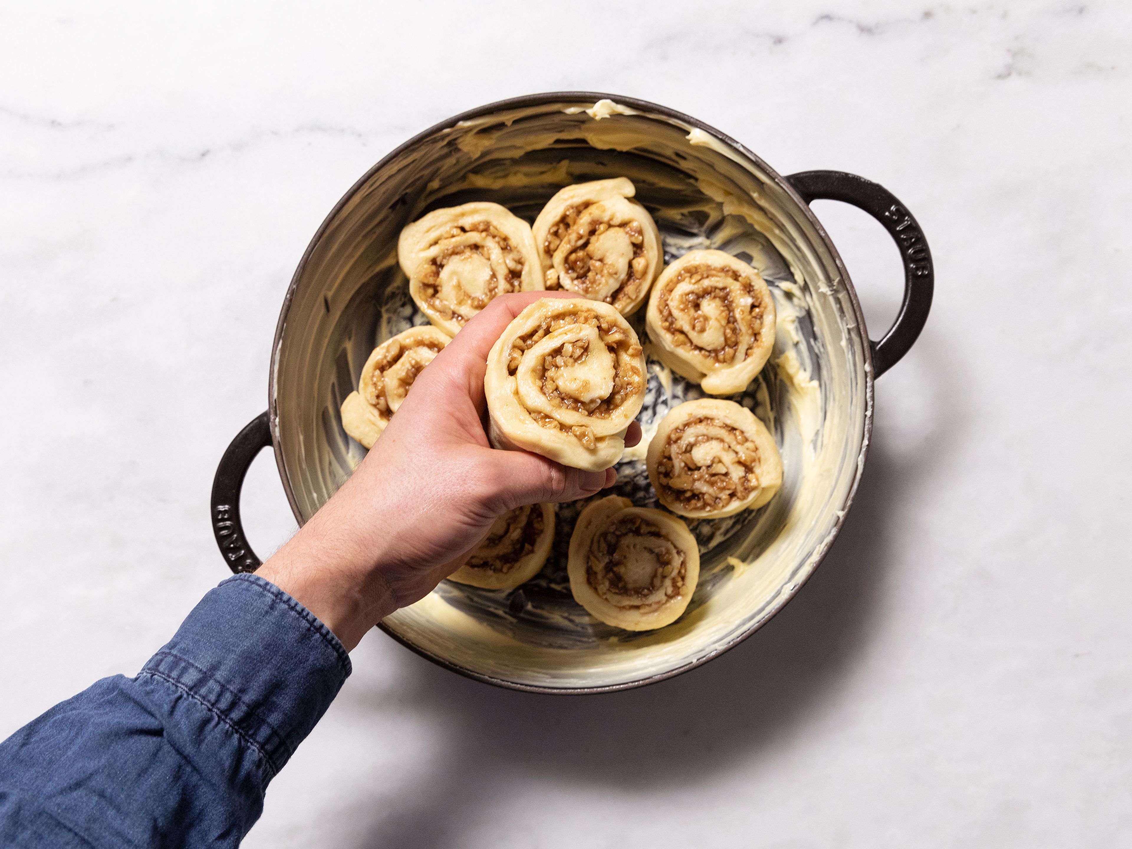 Tightly roll the pastry into a log along the longer edge. Cut the log in 8 equal-sized pieces. Transfer into a cast iron pot and allow to rise for approx. 45 min. more.