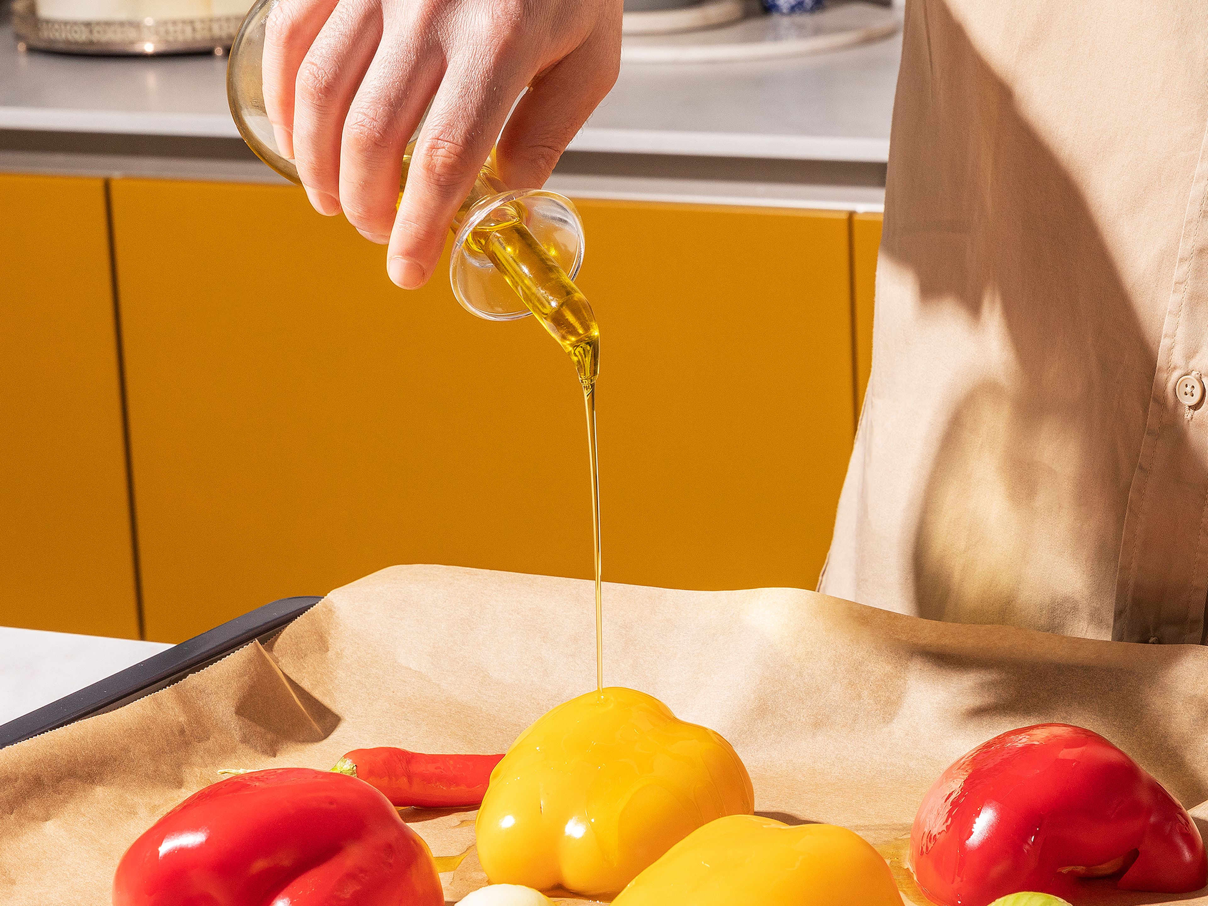 Zwiebel-Viertel, Chilischote und halbierte Paprika auf ein mit Backpapier ausgelegtes Backblech geben. Mit Olivenöl beträufeln und ca. 15 Min. im Ofen garen, bis das Gemüse leicht anbrennt und weich ist.