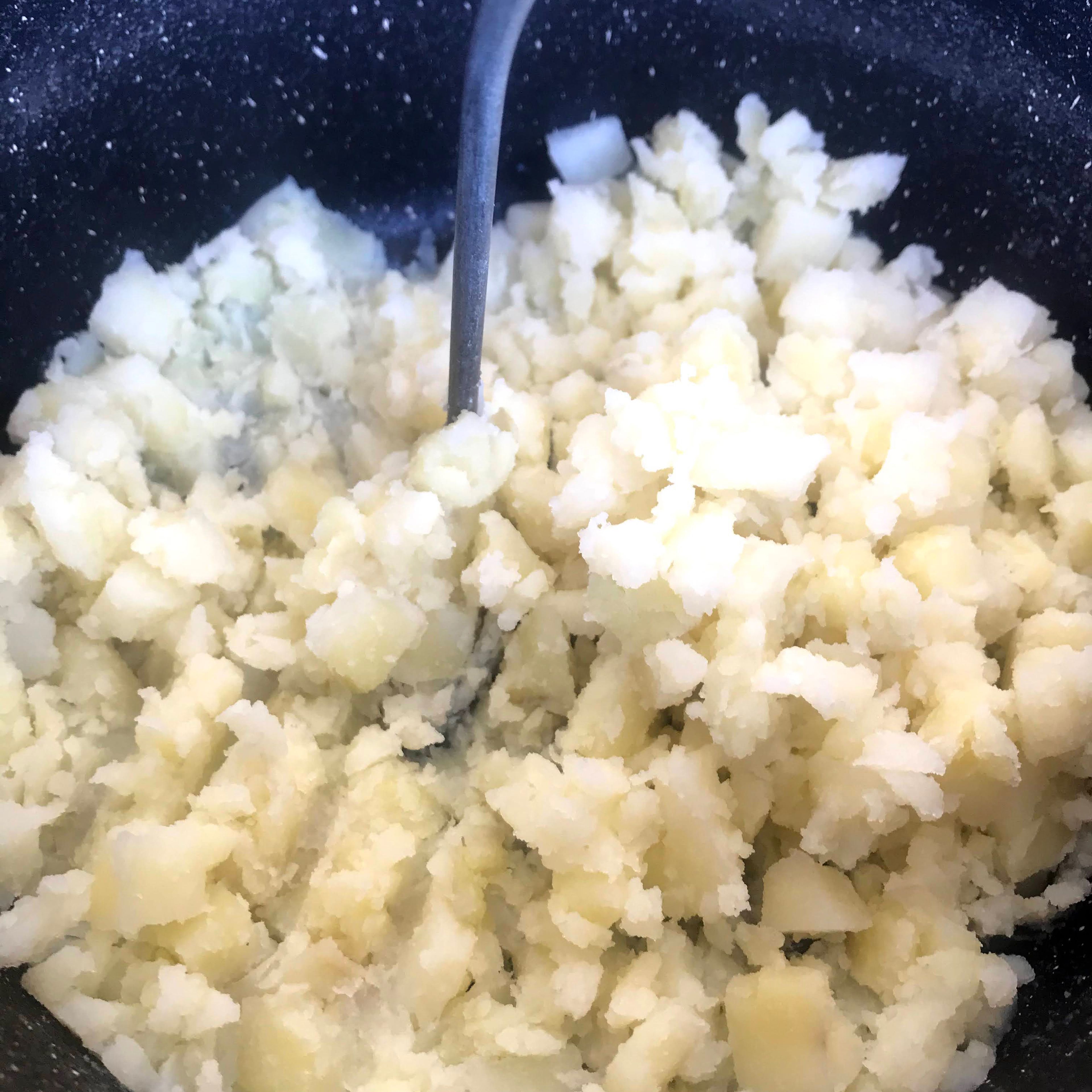 Drain the potatoes, add the milk and mash them until smooth.