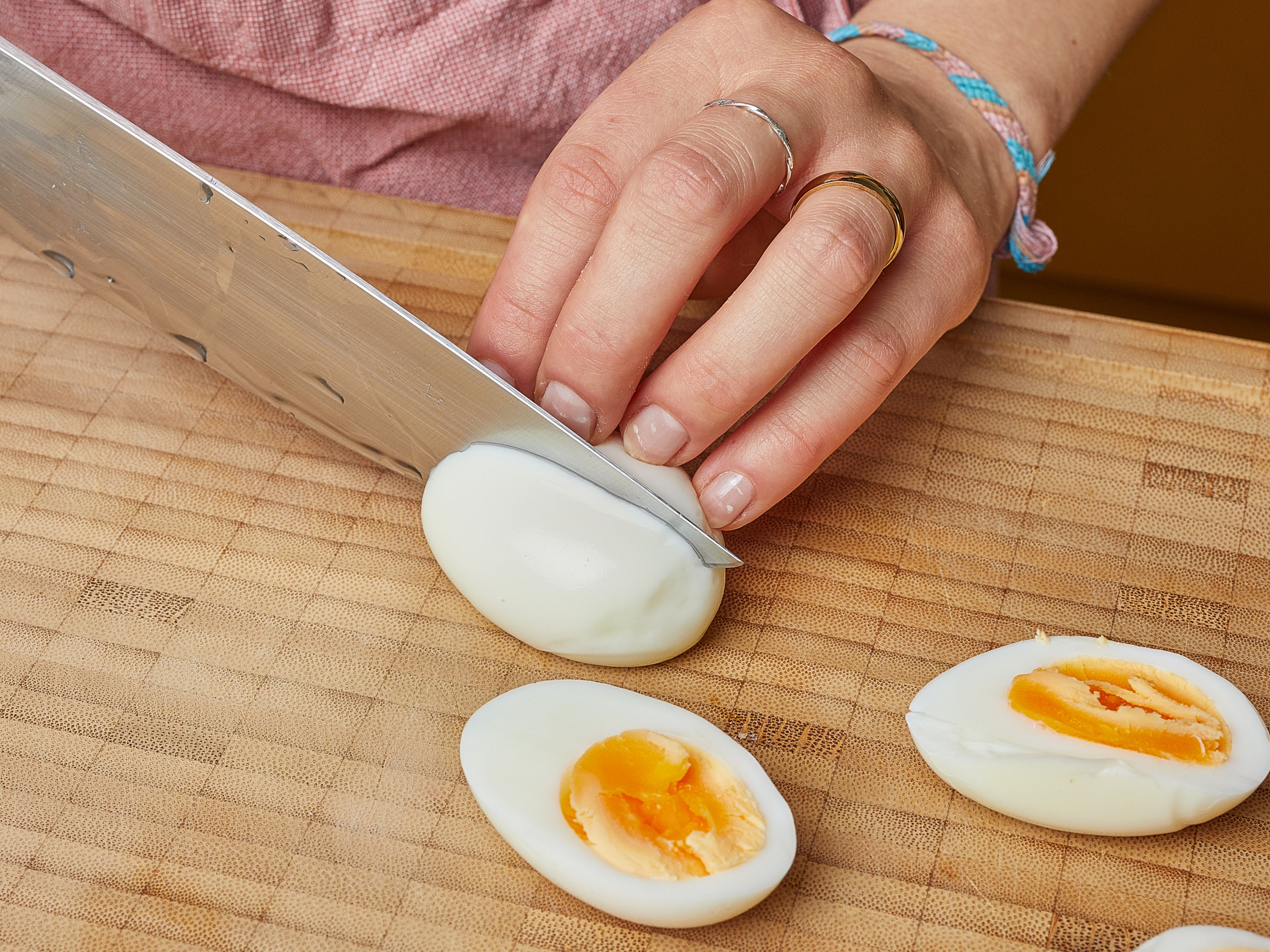 In der Zwischenzeit einen Topf mit Wasser zum Kochen bringen. Die Eier hineingeben und ca. 6–7 Min. kochen, dann herausnehmen und unter fliessendem kaltem Wasser abschrecken. Sobald die Eier abgekühlt sind, schälen, halbieren und beiseite stellen.