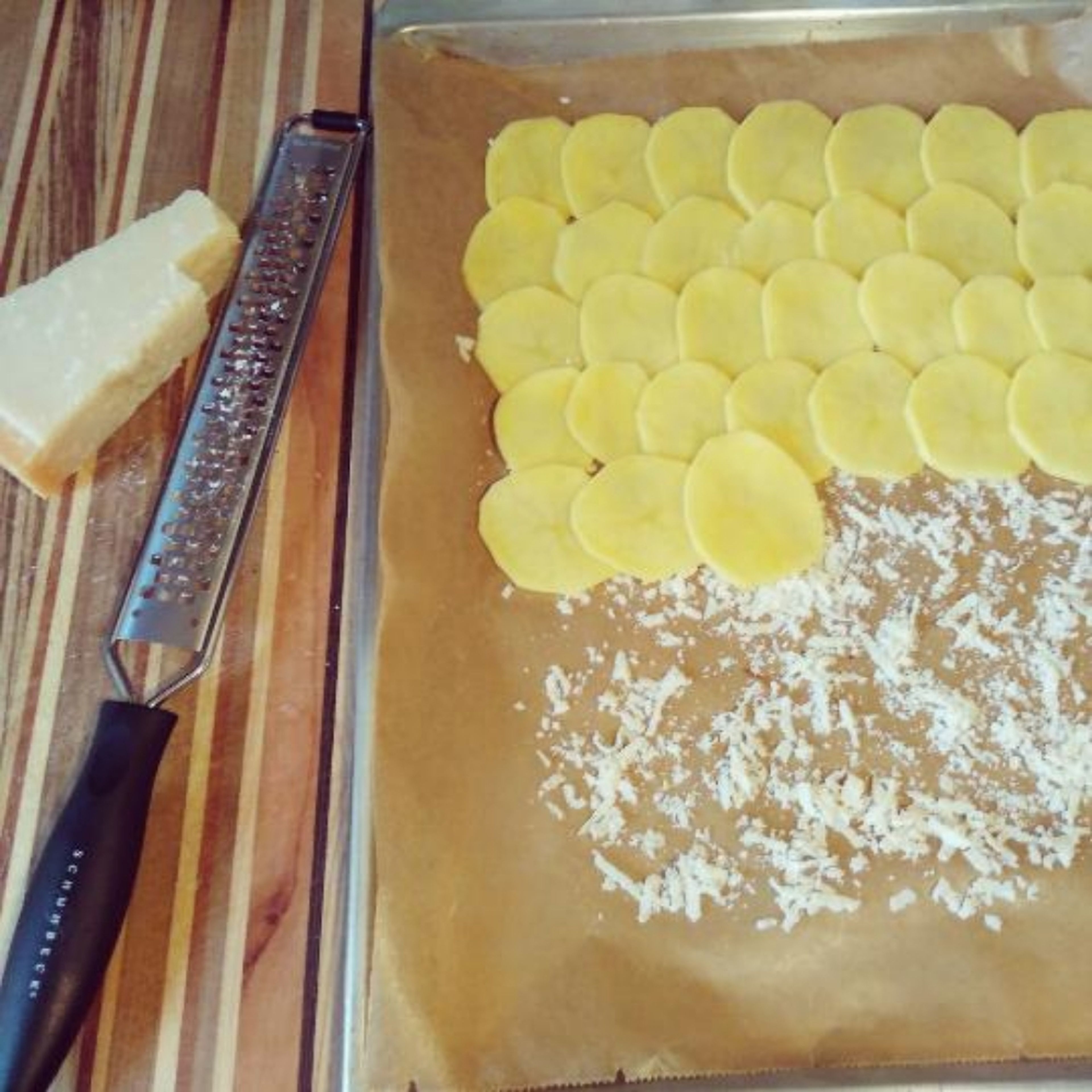 Ofen auf 180° Grad Umluft vorheizen. Auf ein Backpapier Parmesan reiben und verteilen. Kartoffeln schälen, in 2 mm dicke Scheiben hobeln und mit etwas Überlappung auf den Parmesan schlichten. 20 -25 Minuten backen.