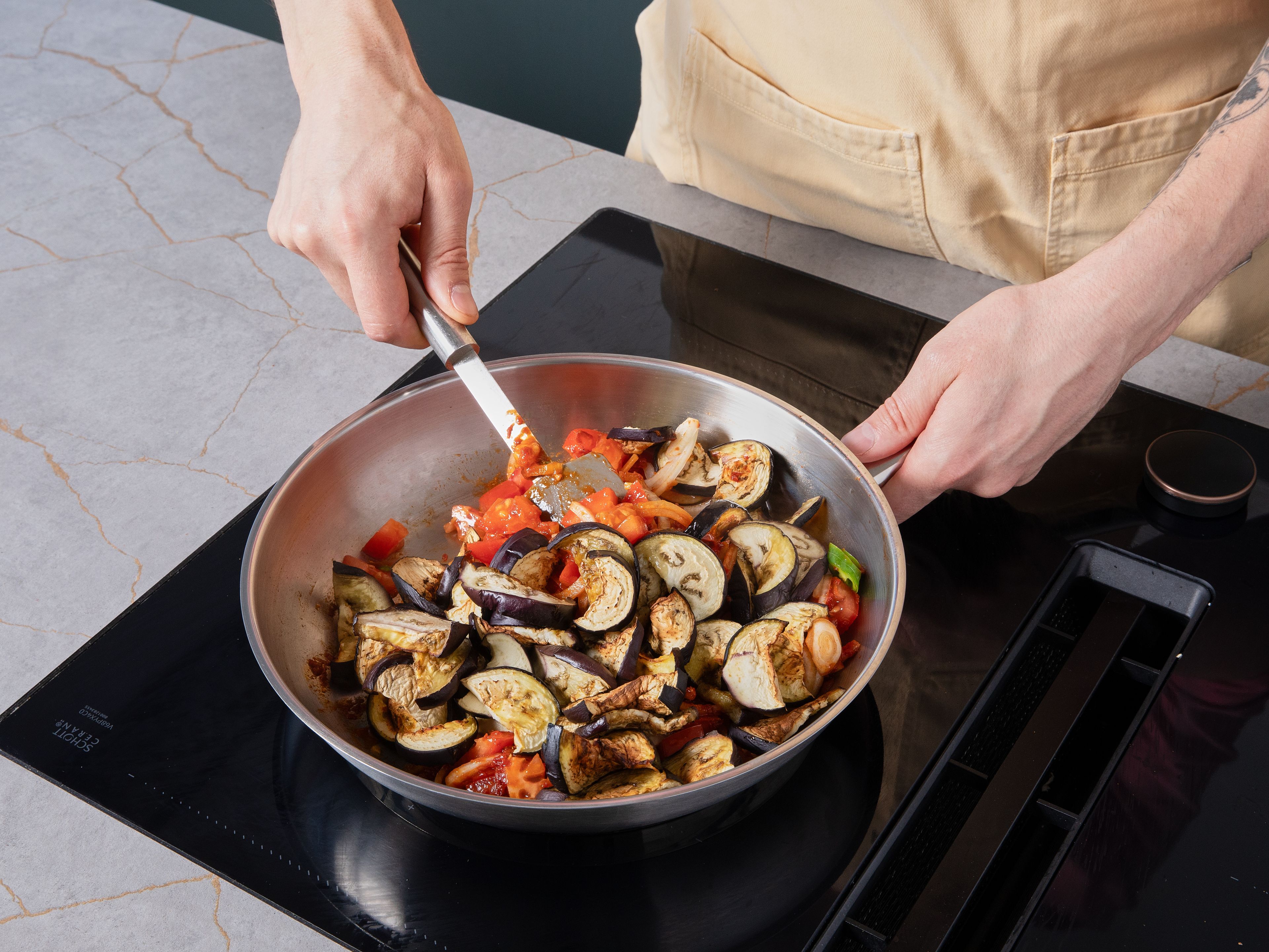 Zwiebel schälen und in feine Ringe schneiden. Tomaten würfeln. Chilischoten und Knoblauch fein hacken. Olivenöl in einer großen Pfanne erhitzen. Knoblauch kurz anbraten, dann Tomatenmark zugeben und ca. 2 Min. mitrösten. Mit Kurkuma, Koriander, Kreuzkümmel, Chilipulver, Zucker, Essig, Salz und Pfeffer würzen. Zwiebeln, Tomaten, Auberginen, Chili und Wasser zugeben. Abgedeckt ca. 15 Min. auf mittlerer Hitze schmoren lassen. Mit Salz und Pfeffer abschmecken.