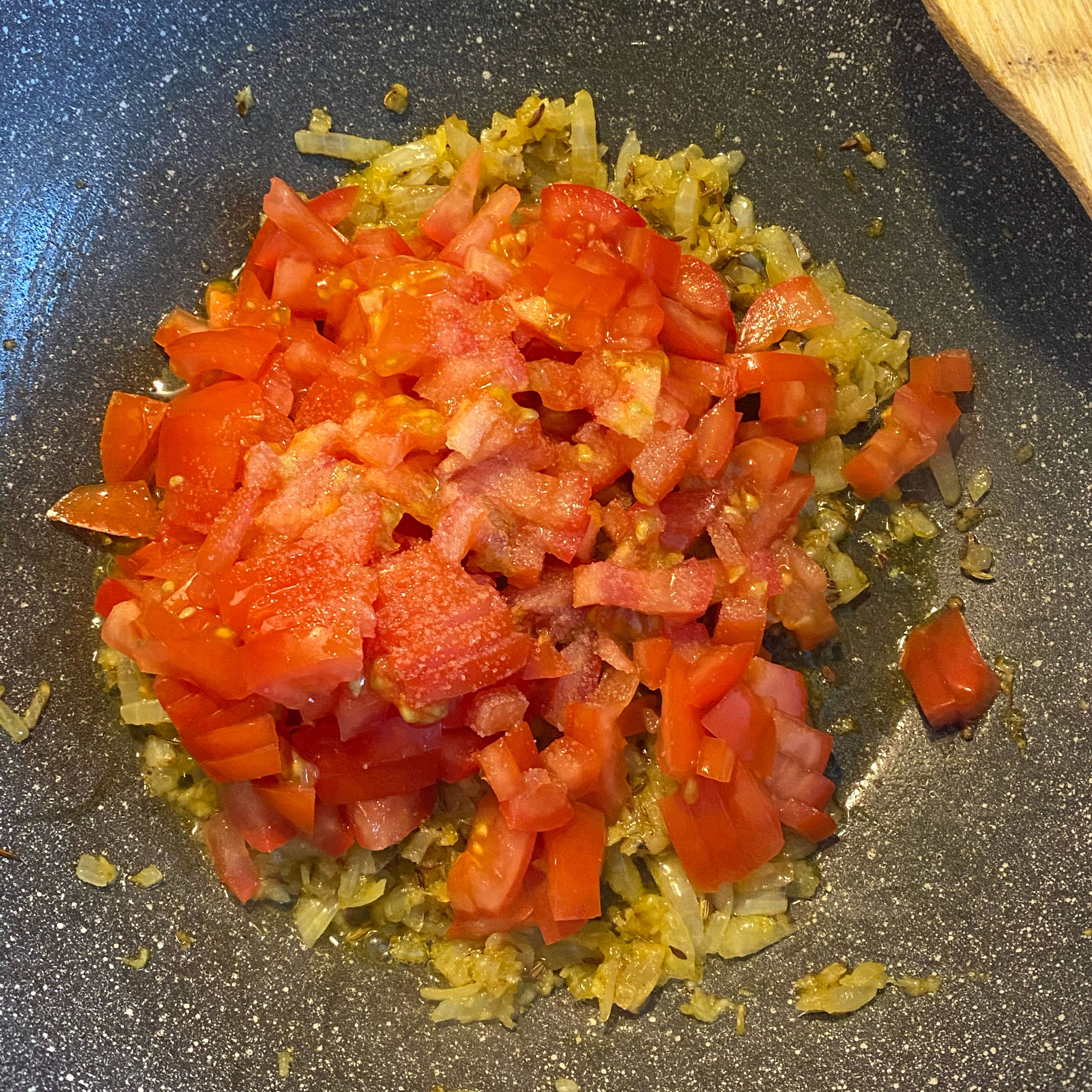 Jetzt gebe die in Stückchen geschnittenen Tomaten und Salz dazu und lasse diese so lange braten bis die Stückchen ganz weich geworden sind. ( Um es zu beschleunigen, schließe einfach den Wok/die Pfanne mit einem Deckel.)