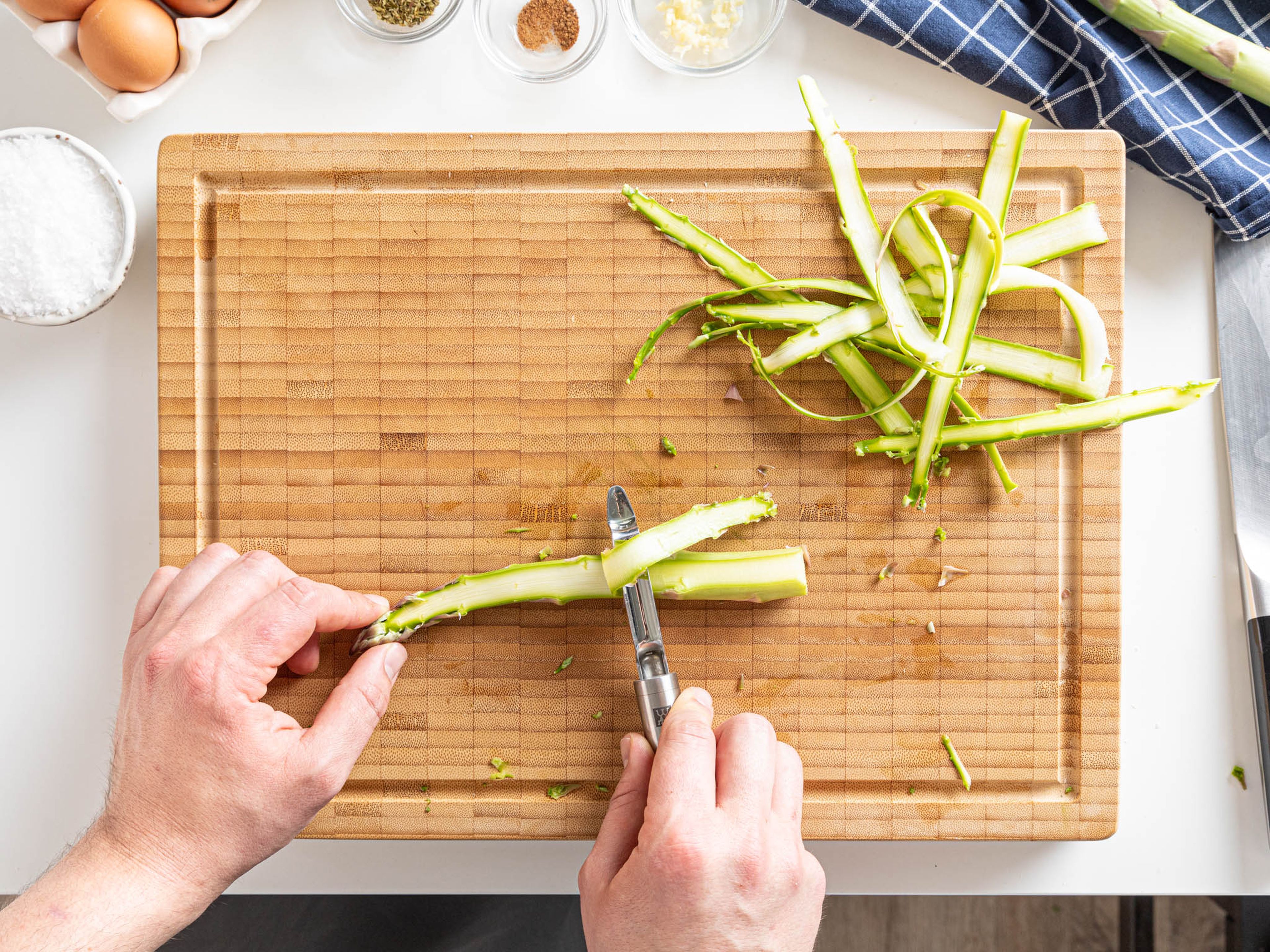 Coarsely grate the Parmesan, chop the garlic, and halve the cherry tomatoes. Finely chop the parsley. Cut off the woody ends of the green asparagus, then use a vegetable peeler to carefully shave long lengths of asparagus.