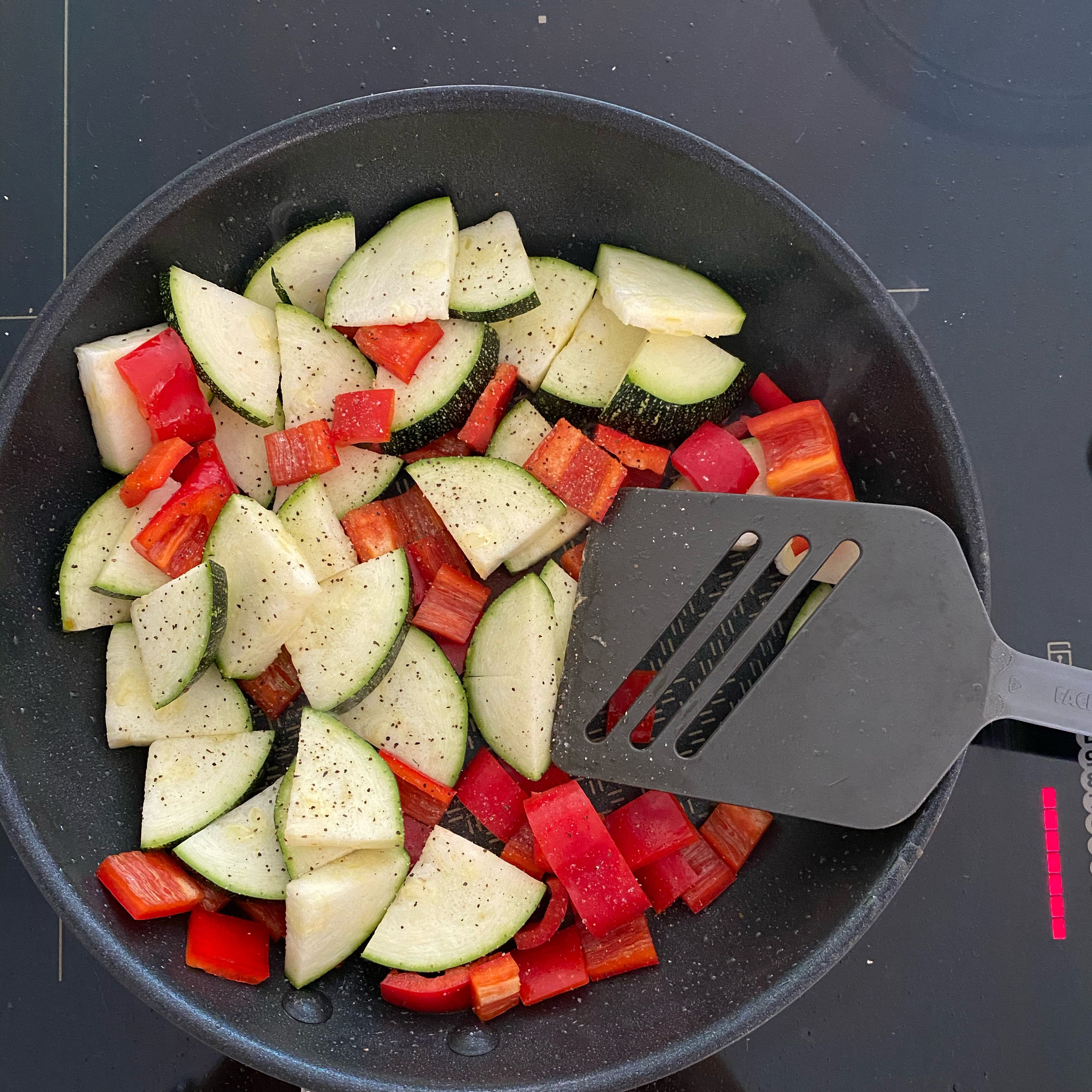 Die geschnittenen Paprika und Zucchini Scheiben in eine Pfanne geben mit Salz und Pfeffer würzen und langsam anbraten.