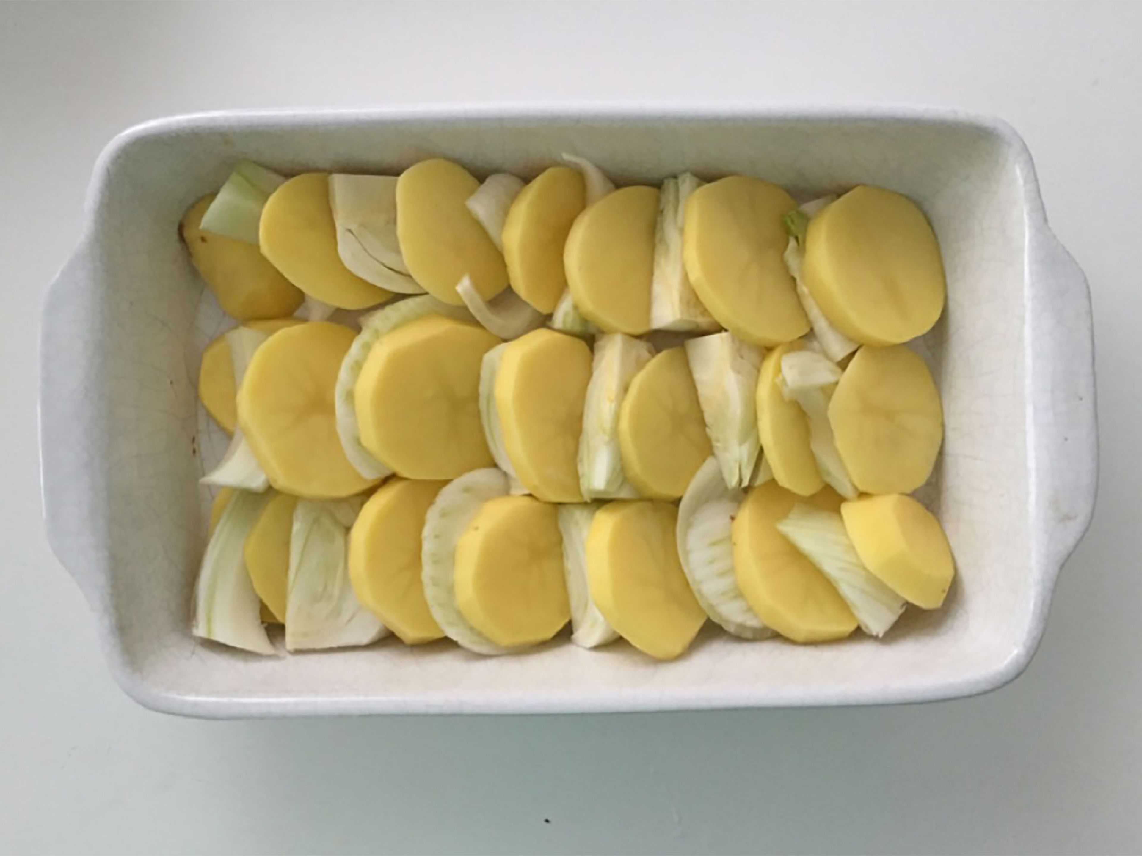 Kartoffeln (schälen) und Fenchel in dünne Scheiben schneiden und in der Auflaufform verteilen. Anschließend mit Pfeffer und Salz würzen.