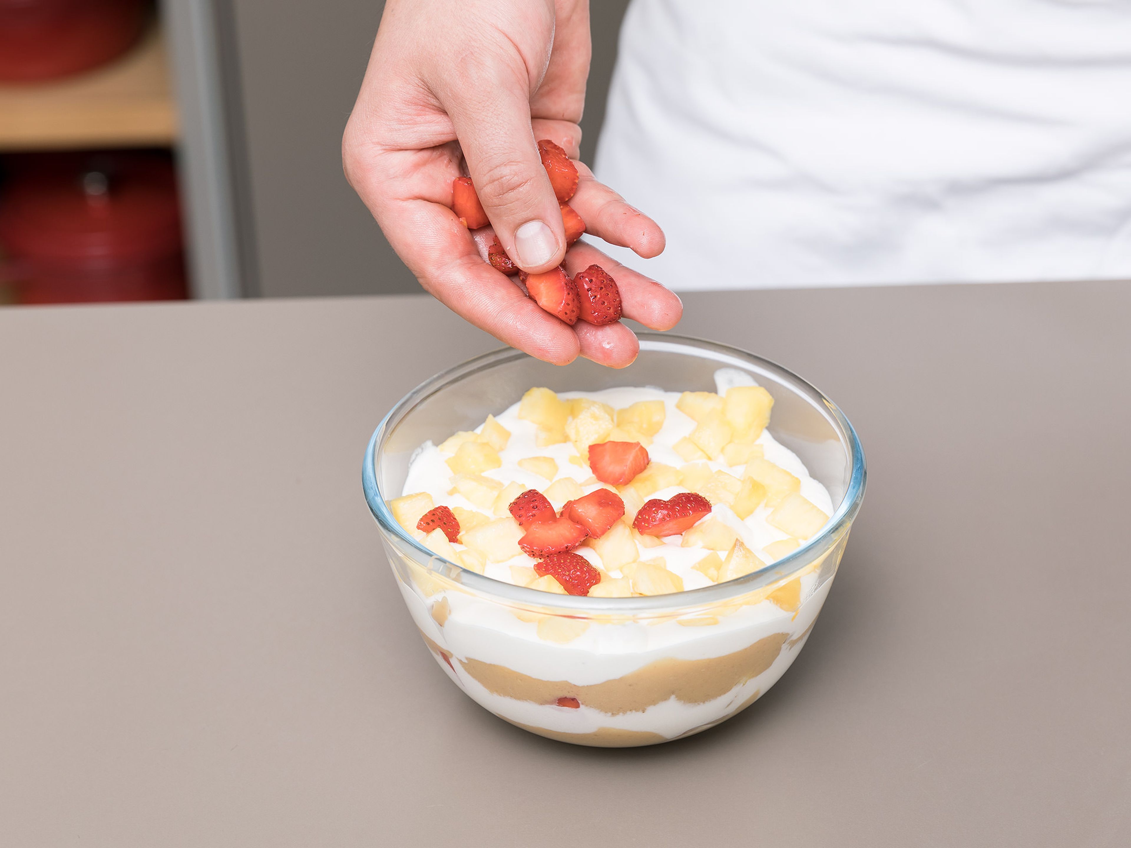 In a bowl, crush digestive biscuits by hand into approx. 2-cm/1-inch. pieces. Add half of the biscuit to the bottom of a serving bowl, then layer with half of the toffee mixture, half of the whipped cream, and add half of the pineapple and strawberry pieces on top. Repeat layers until everything is used up. Enjoy!