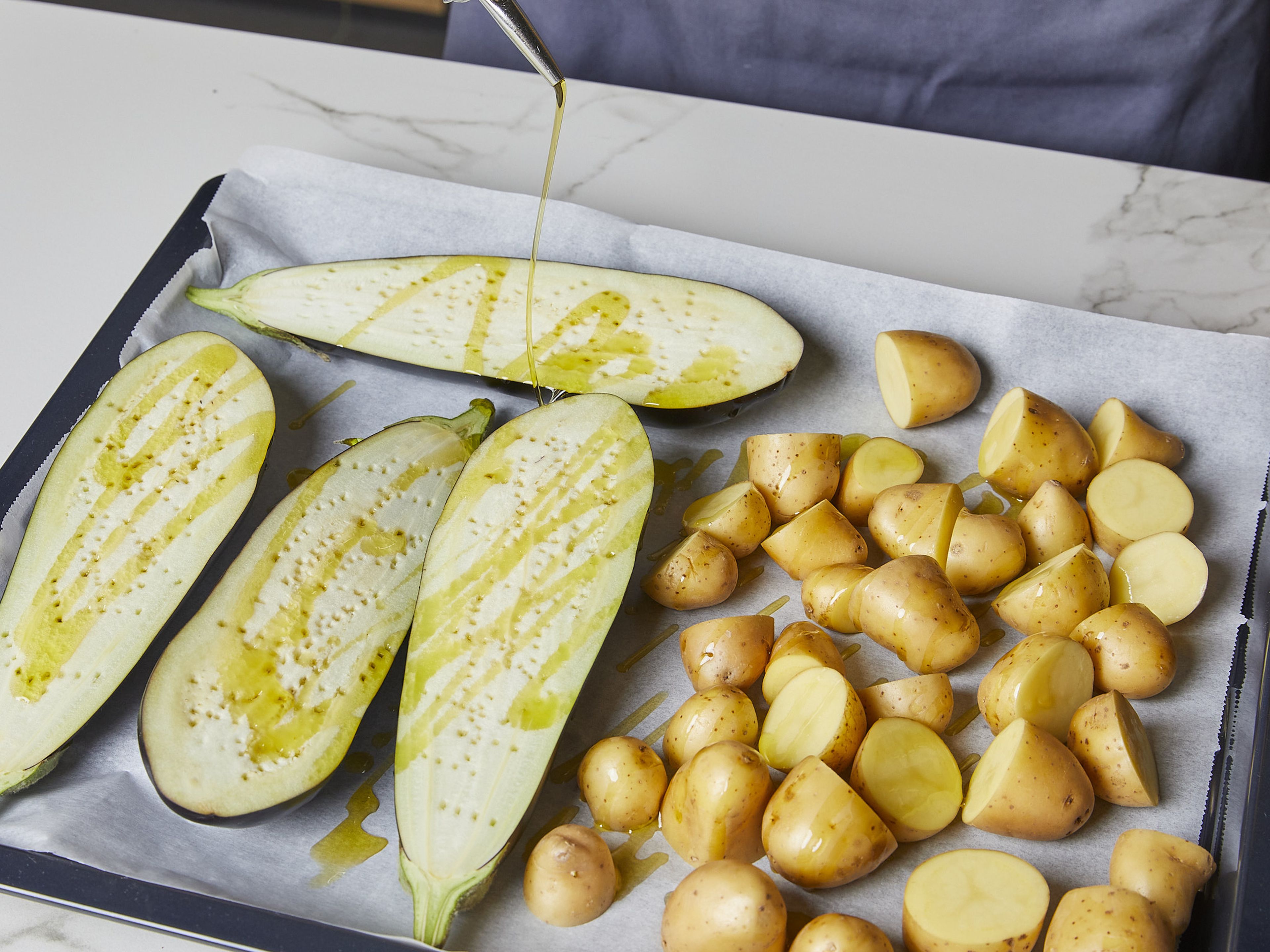 Cut eggplants in half lengthwise and pierce the cut surface several times with a fork. Place the eggplants on the baking sheet cut-side up. Drizzle with more olive oil and bake in the oven with the potatoes for approx. 40–50 min. or until the potatoes are golden brown and the eggplants are soft. In the last 10 min. of the baking time, add the unpeeled garlic cloves to the baking sheet.