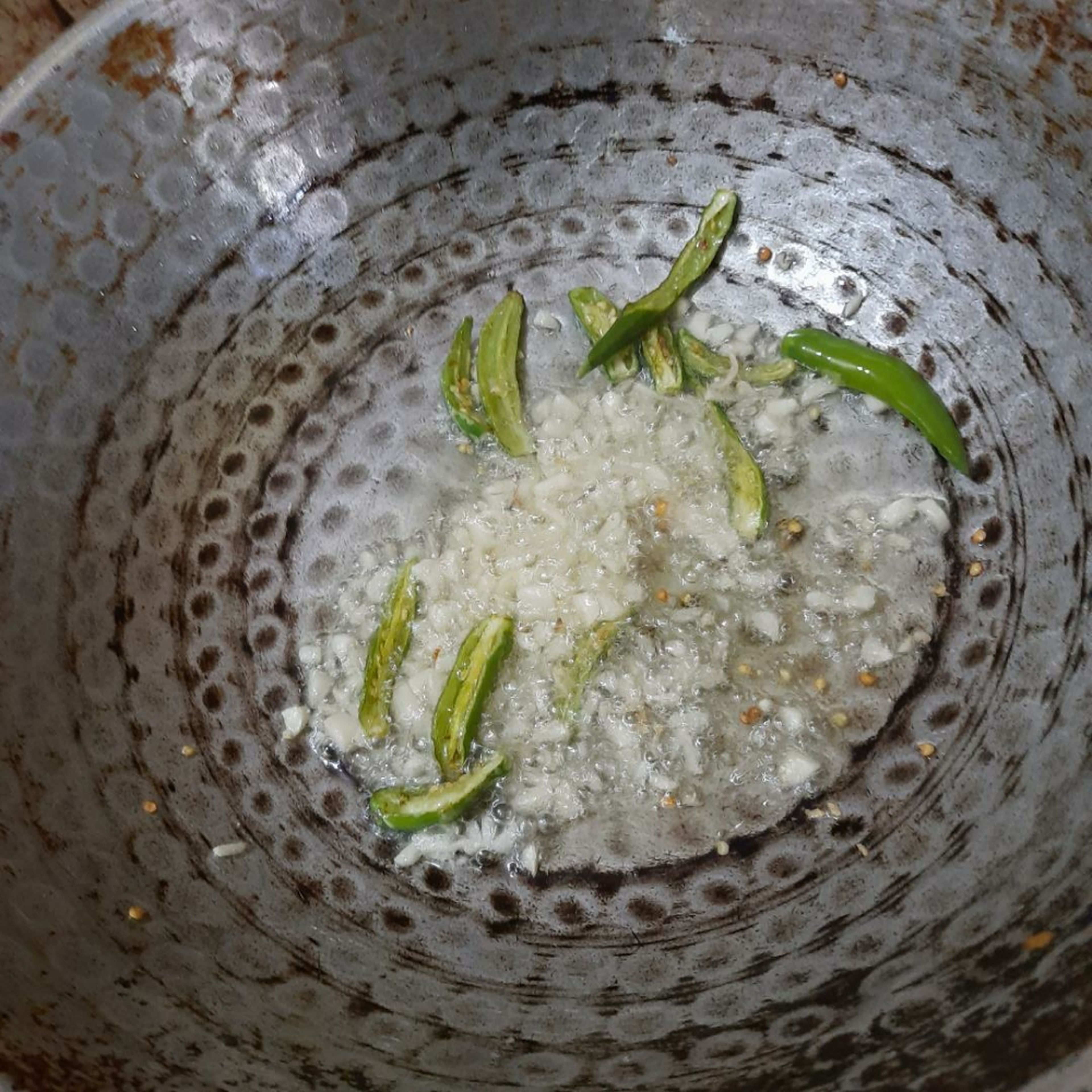 Heat the oil in the pan. Once heated, add the chopped garlic and green chillies.