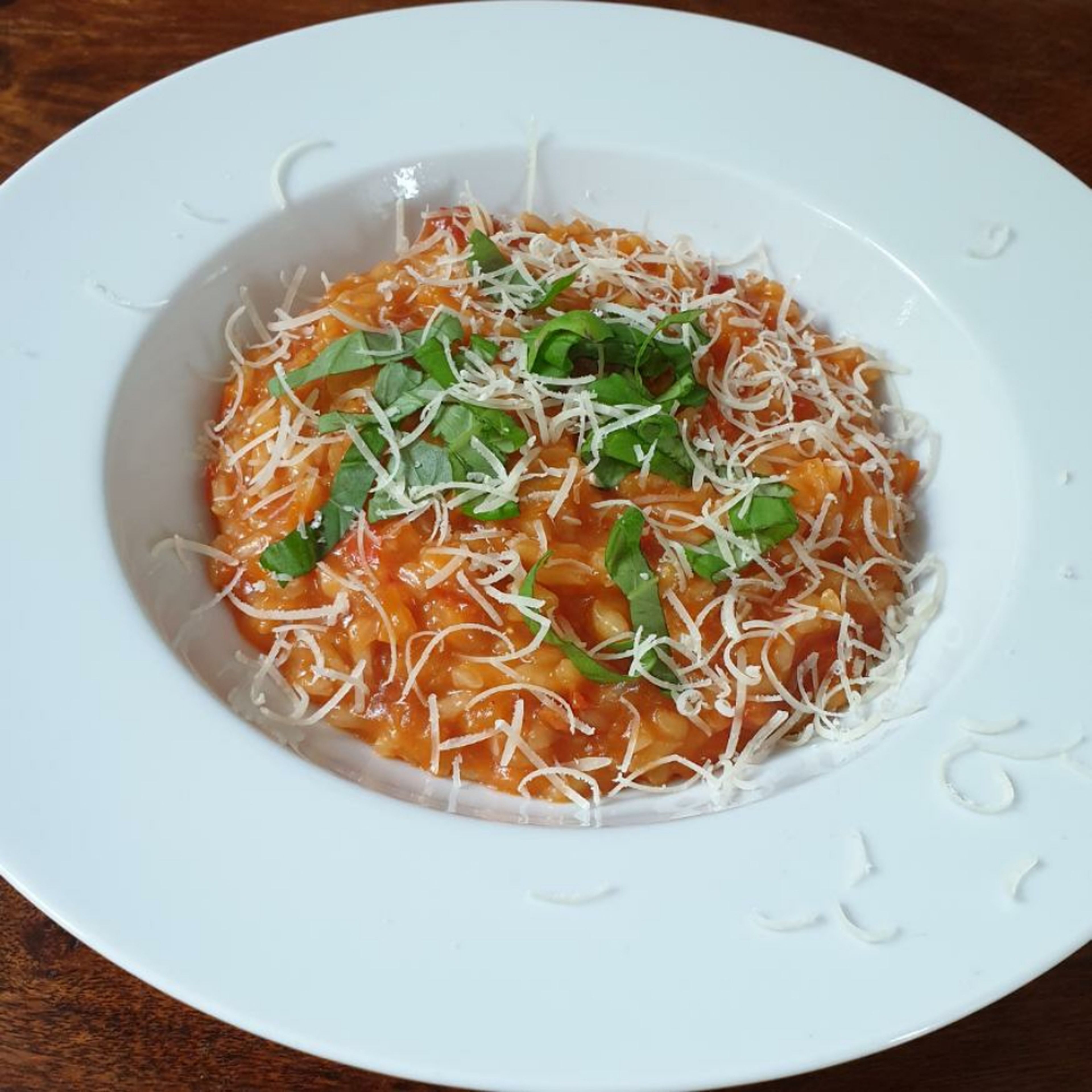 Das Risotto auf den Teller geben und mit dem restlichen Parmesan und dem fein geschnittenen Basilikum garnieren. Guten Appetit!