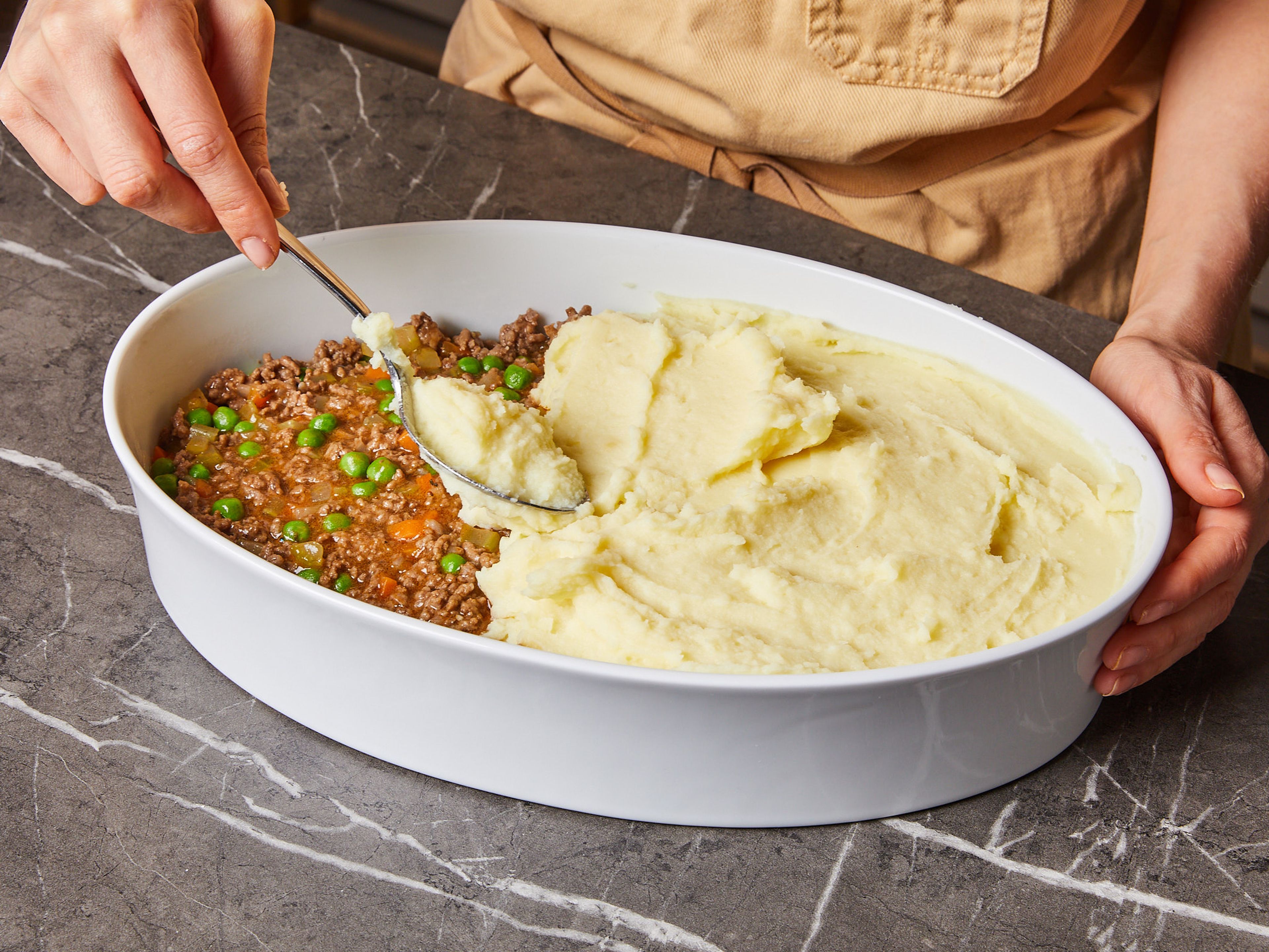 Add the peas in. Transfer everything to a baking dish and evenly cover with mashed potatoes. Sprinkle Parmesan on top and bake for approx. 20 min in the preheated oven until golden brown.