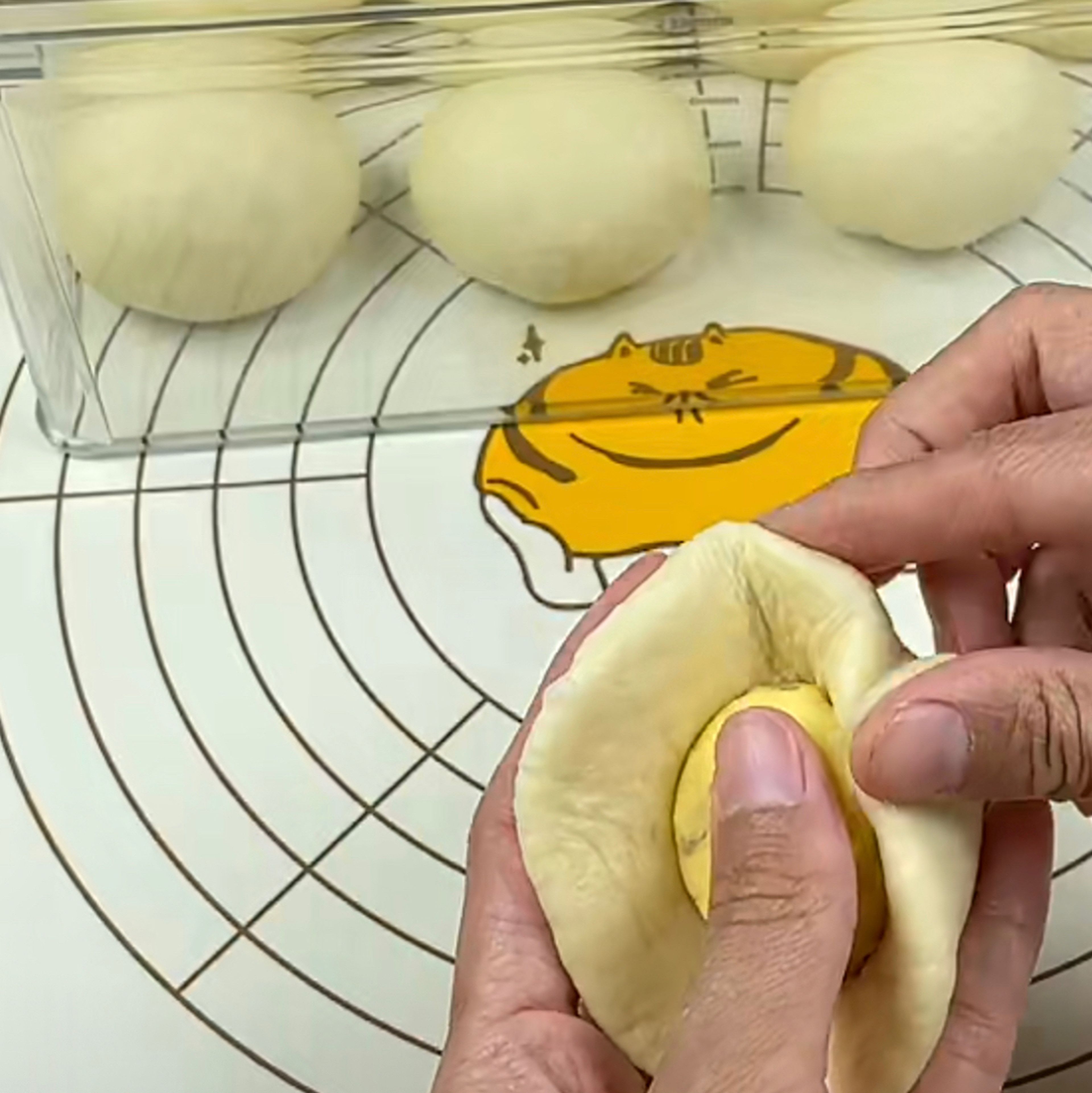 On a clean surface, roll out each dough ball to a flat circle and put about 25g custard filling in the middle then wrap it.