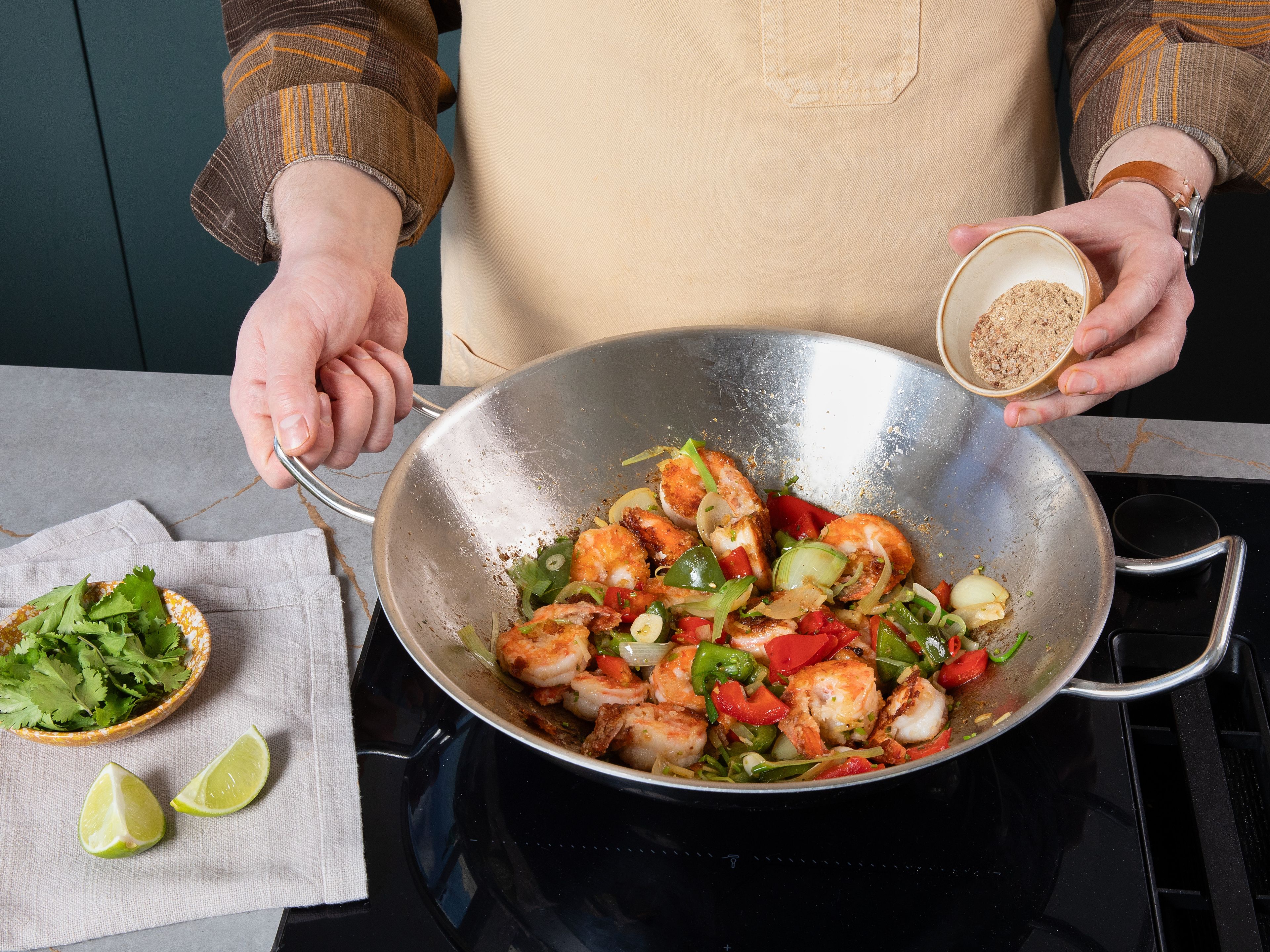 In the same wok, add some more oil, and then add onion and red and green peppers, season with salt and pepper, and fry for approx. 4 min. Then, add garlic, ginger, coriander stalks, spring onion whites, half of thai chilli, and then fry for another approx. 2 min. Then, add shrimp and, whilst stirring, sprinkle over spice mix to ensure it is evenly spread, and fry for approx. 1 min. Finally, squeeze in lime and stir in most of coriander leaves and spring onion greens. Serve with rice, and garnish with more coriander leaves and remaining thai chilli.