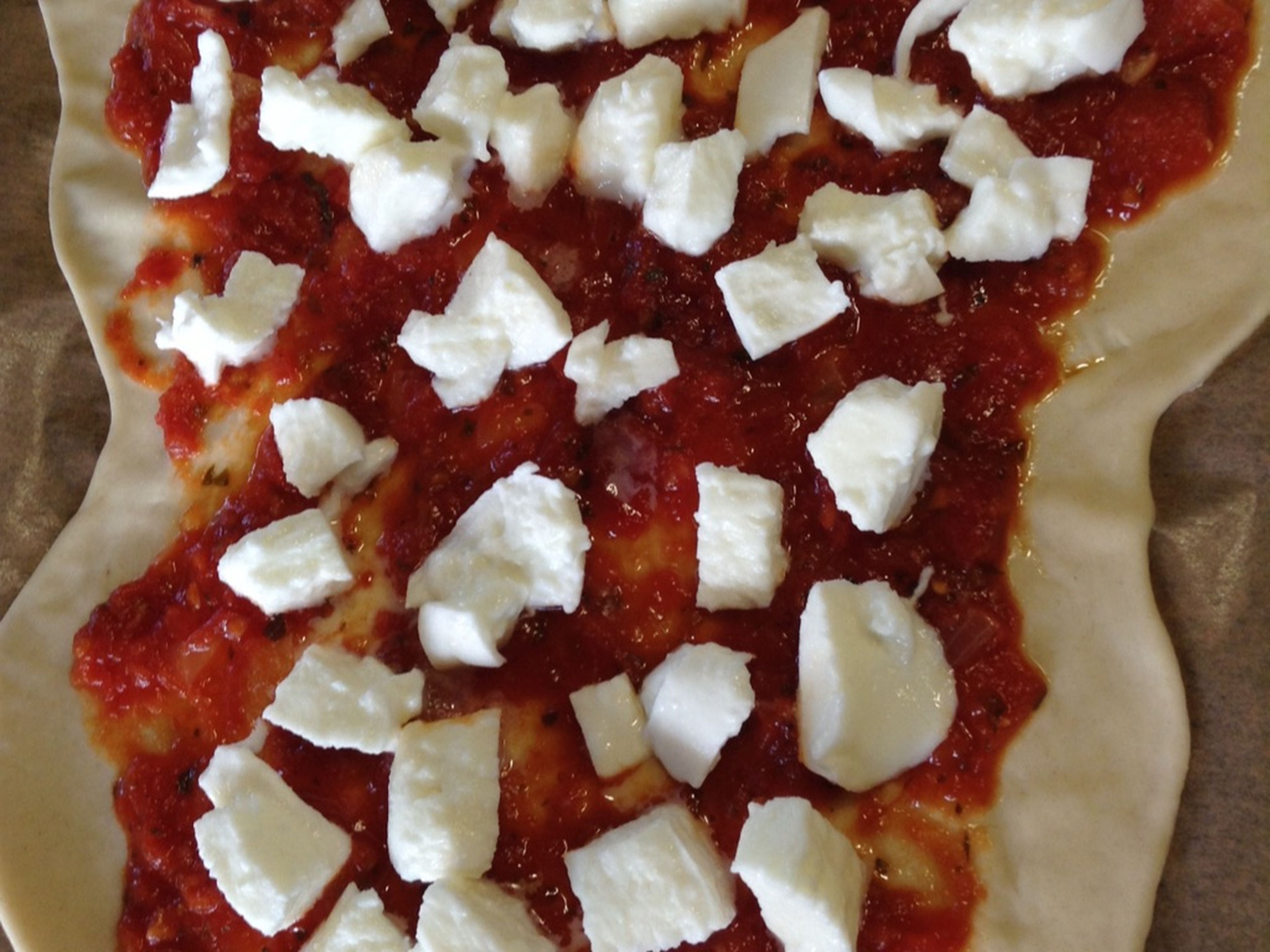 Nun kommt der Käse auf die Pizza. Ihr könnt jeden geriebenen Käse nehmen, den ihr wollt. Frischen Mozzarellakäse könnt ihr einfach mit den Händen zerkleinern und auf der Pizza verteilen.