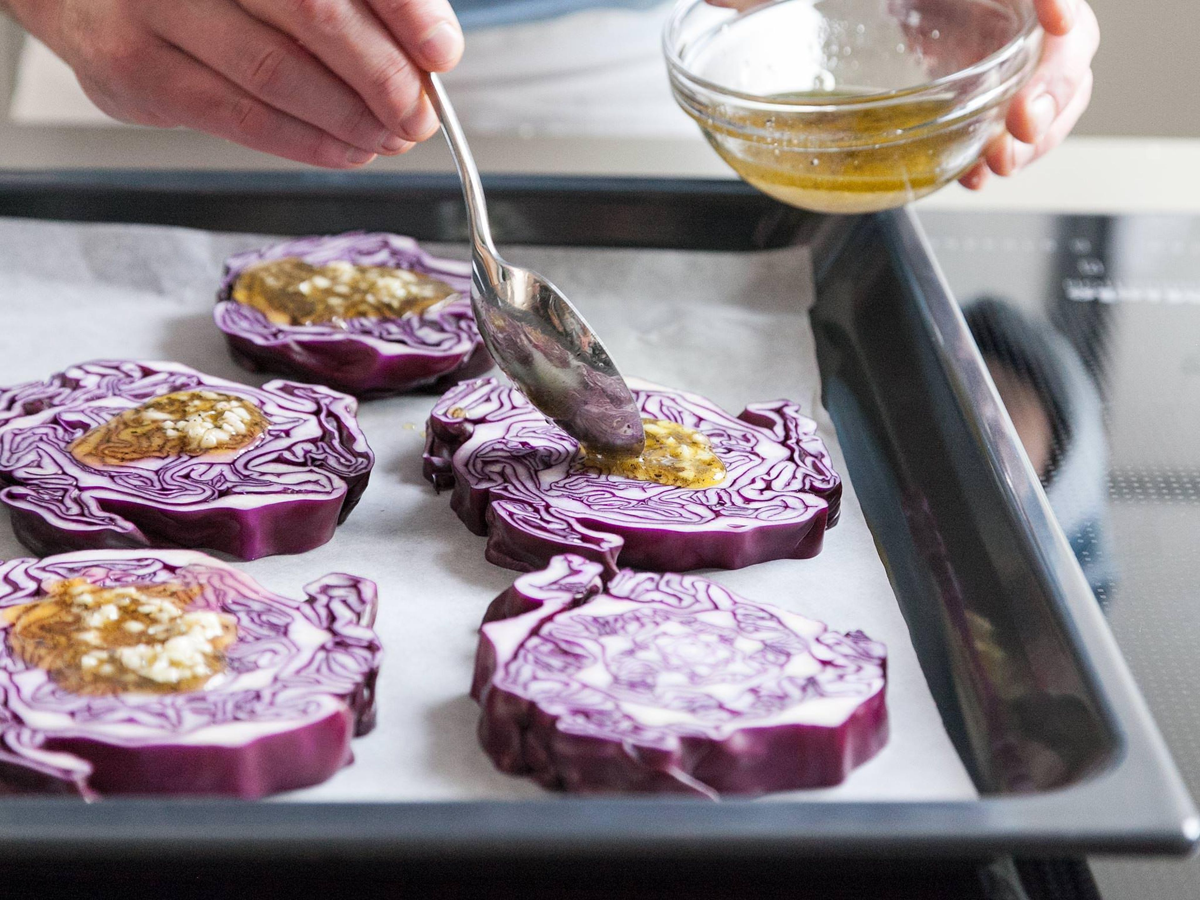 Transfer red cabbage slices onto a parchement-lined baking sheet and brush with garlic-oil mixture.