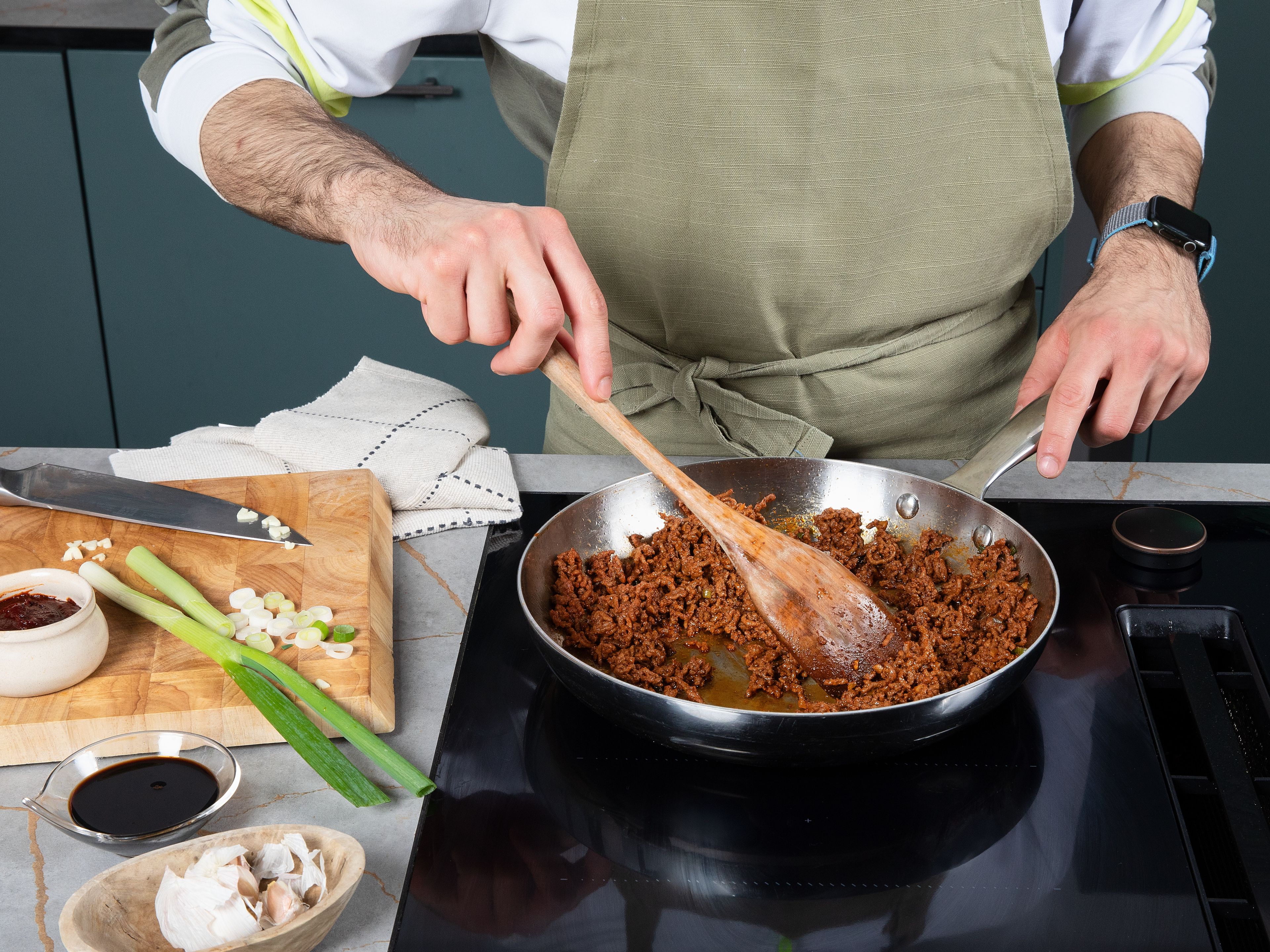 Peel and chop garlic finely. Cut scallions into fine rings and set some green parts aside for garnish. Heat oil in a pan and fry garlic and scallions until translucent. Then, add chili bean paste and fry for approx. 2 min more. Add ground beef and continue frying until thoroughly cooked for approx. 8 min. Deglaze with soy sauce and set aside.