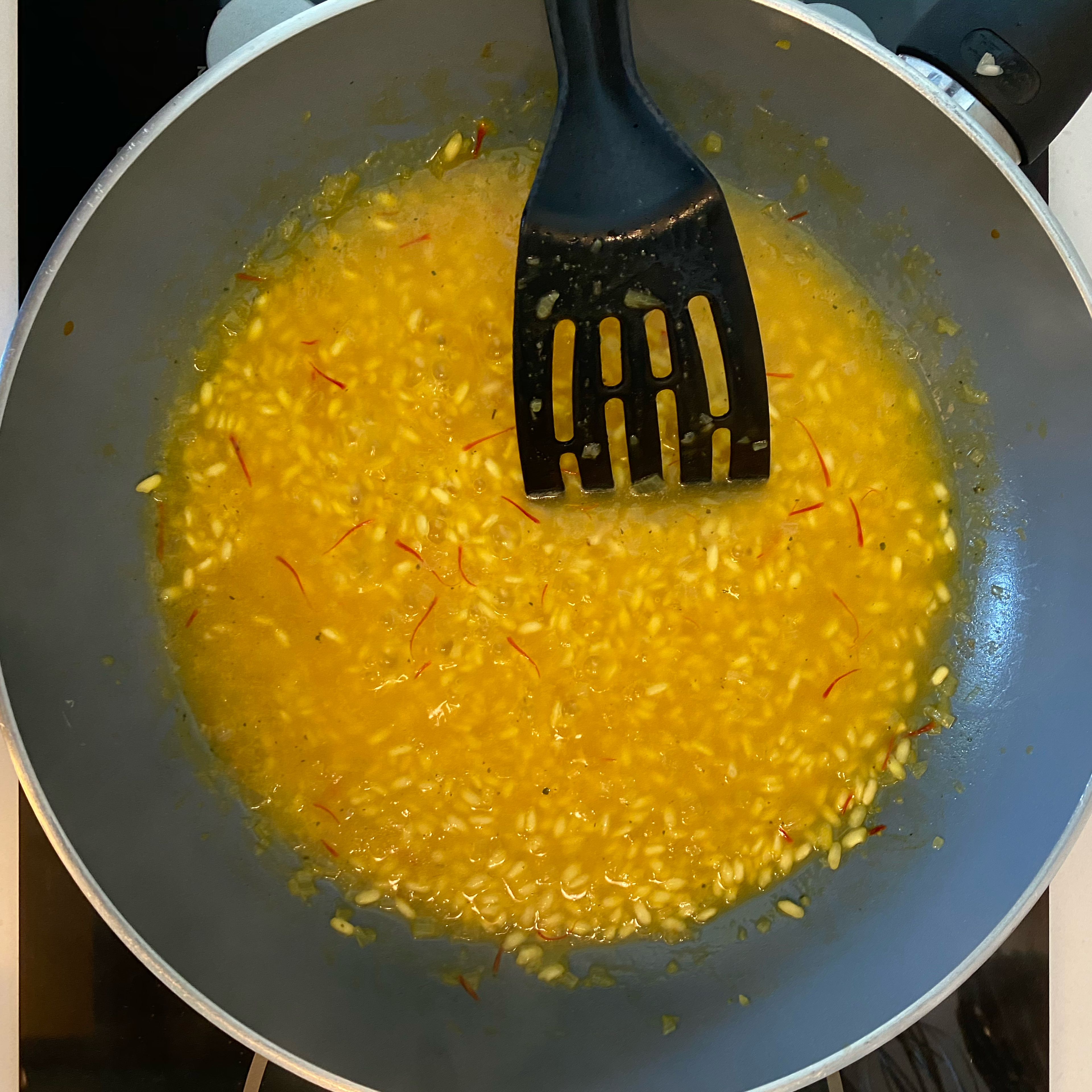 Once the shallot is stewed, pour the rice and toast it for 3-4 minutes, so the beans will seal and cook well. Pour in the white wine and let it evaporate completely. At this point add a half of the water with the saffron pistils that you have infused and then proceed with the cooking for about 18-20 minutes, adding the broth one ladle at a time, as needed, as it will be absorbed by the rice, the beans must always be covered with broth.