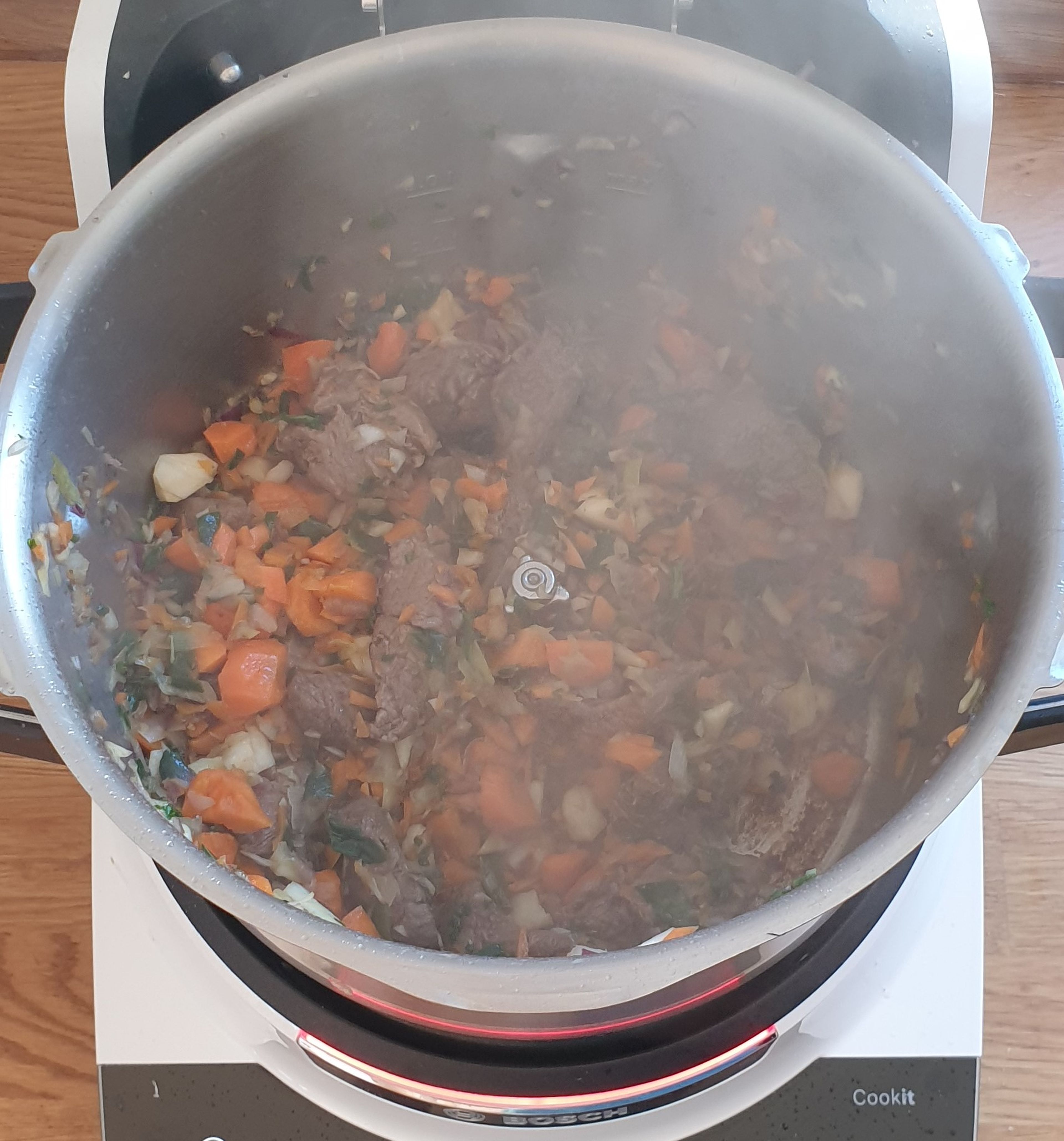 Das Gemüse wieder dazugeben und das Tomatenmark hinzufügen. Alles bei geöffnetem Deckel anbraten (ohne Werkzeug | 150°C | 3 Minuten). Wieder ab und zu mit dem Küchenspatel umrühren.