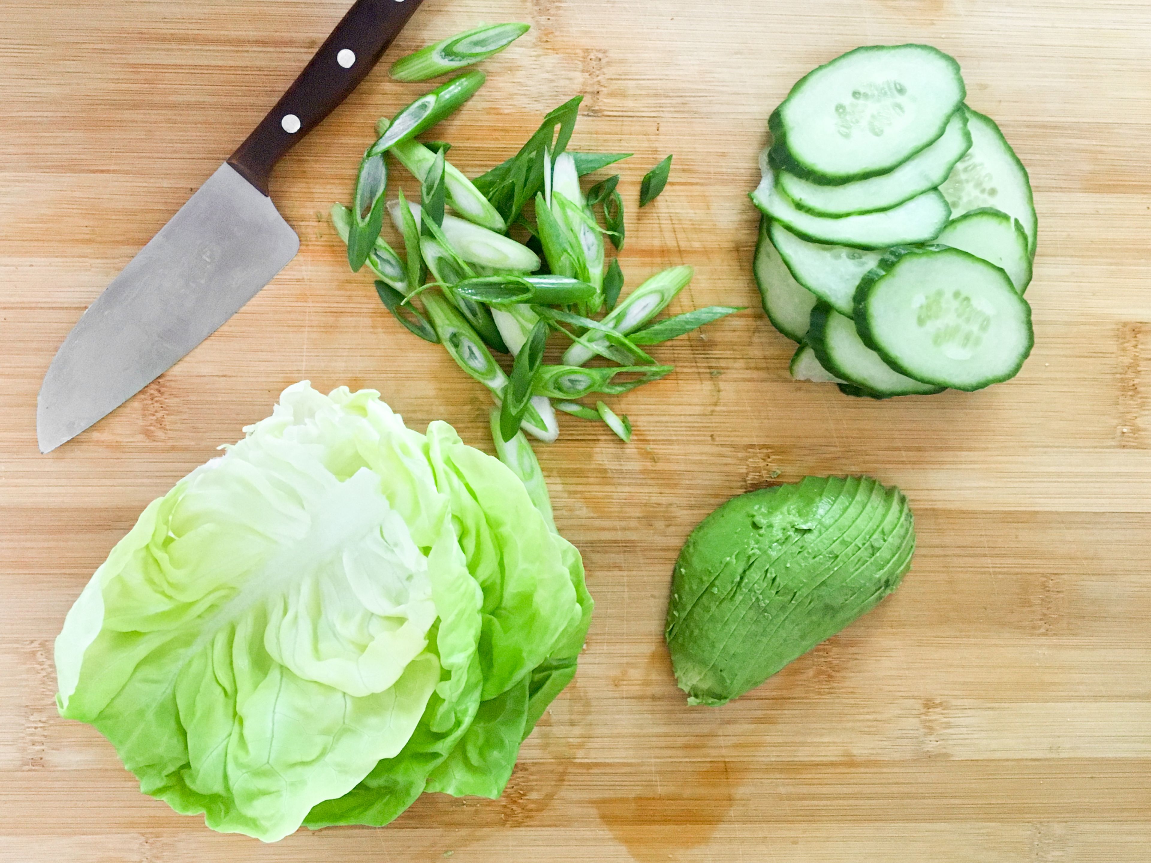 Cut the cucumber into slices. Wash the salad and pluck into large pieces. Halve avocado, remove core and take out pulp with a spoon. Then cut into slices. Cut scallion into rings.