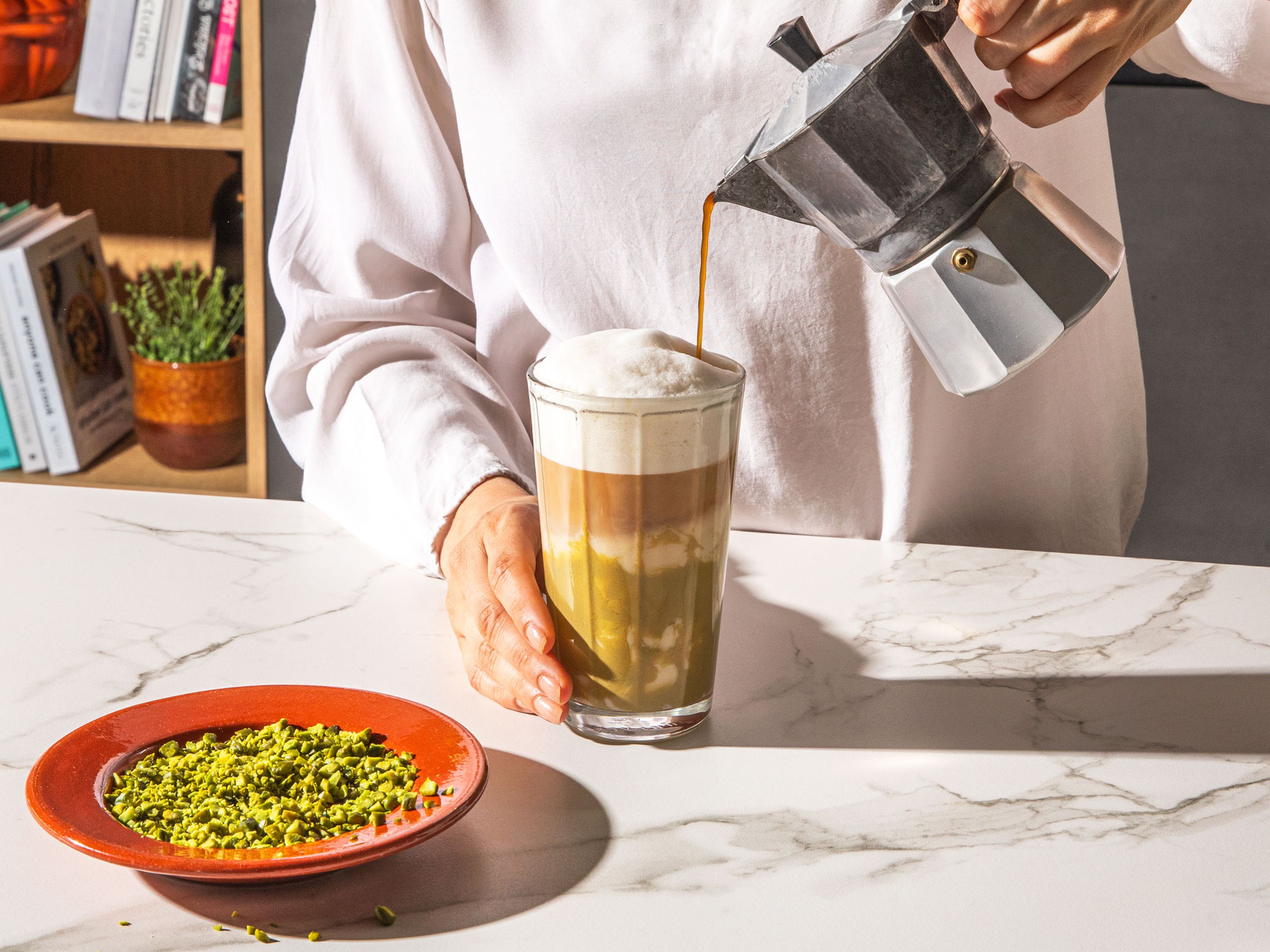 Espresso langsam in den Schaum gießen und mit fein gehackten Pistazien garnieren.