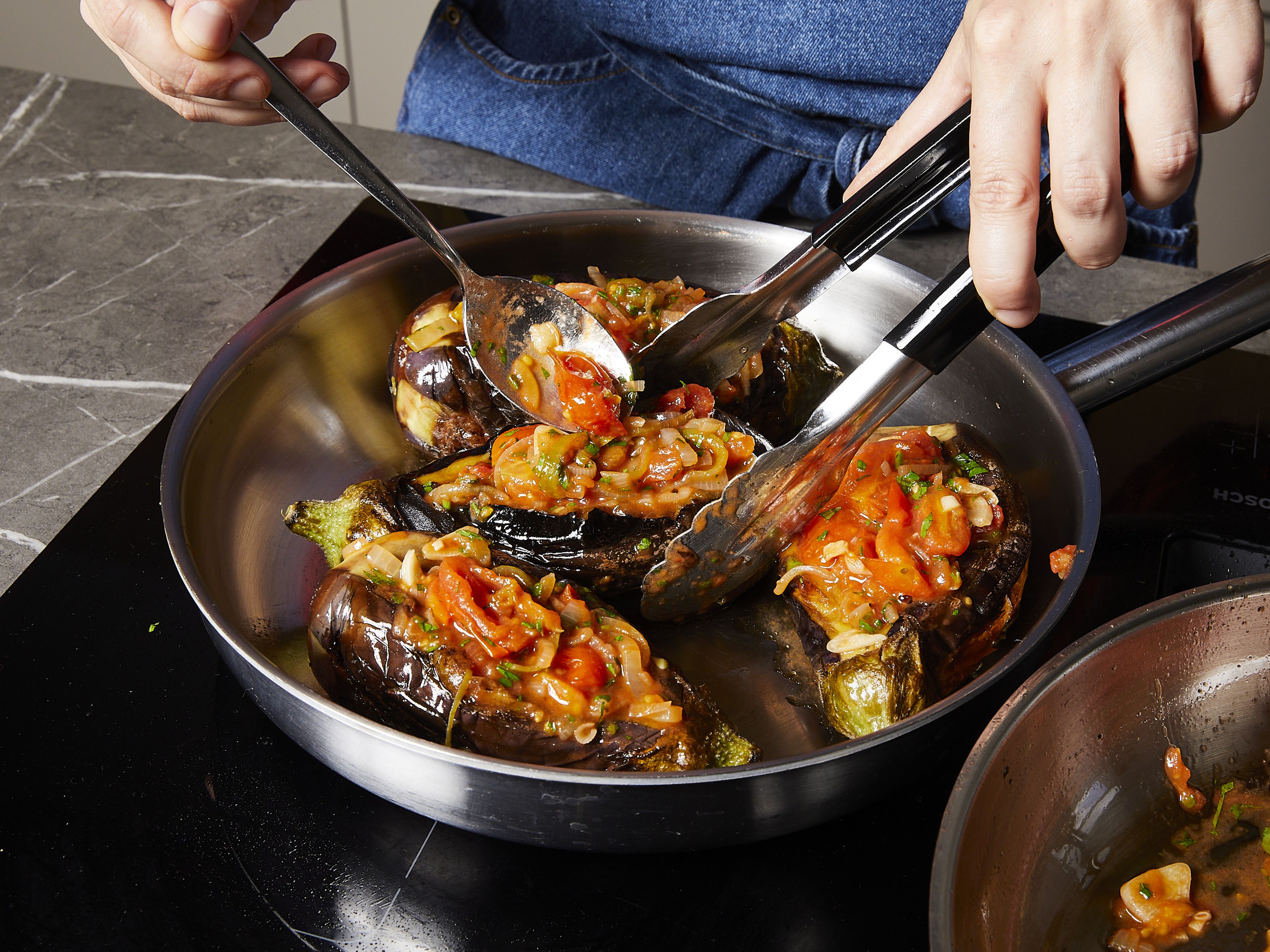 Fry the eggplants on all sides in the pan over a medium heat for approx. 5 mins. per side. Then cut the eggplants lengthwise and carefully open them like a baguette, taking care not to cut the eggplants all the way through. Spoon the filling into the eggplants and place them back in the pan.