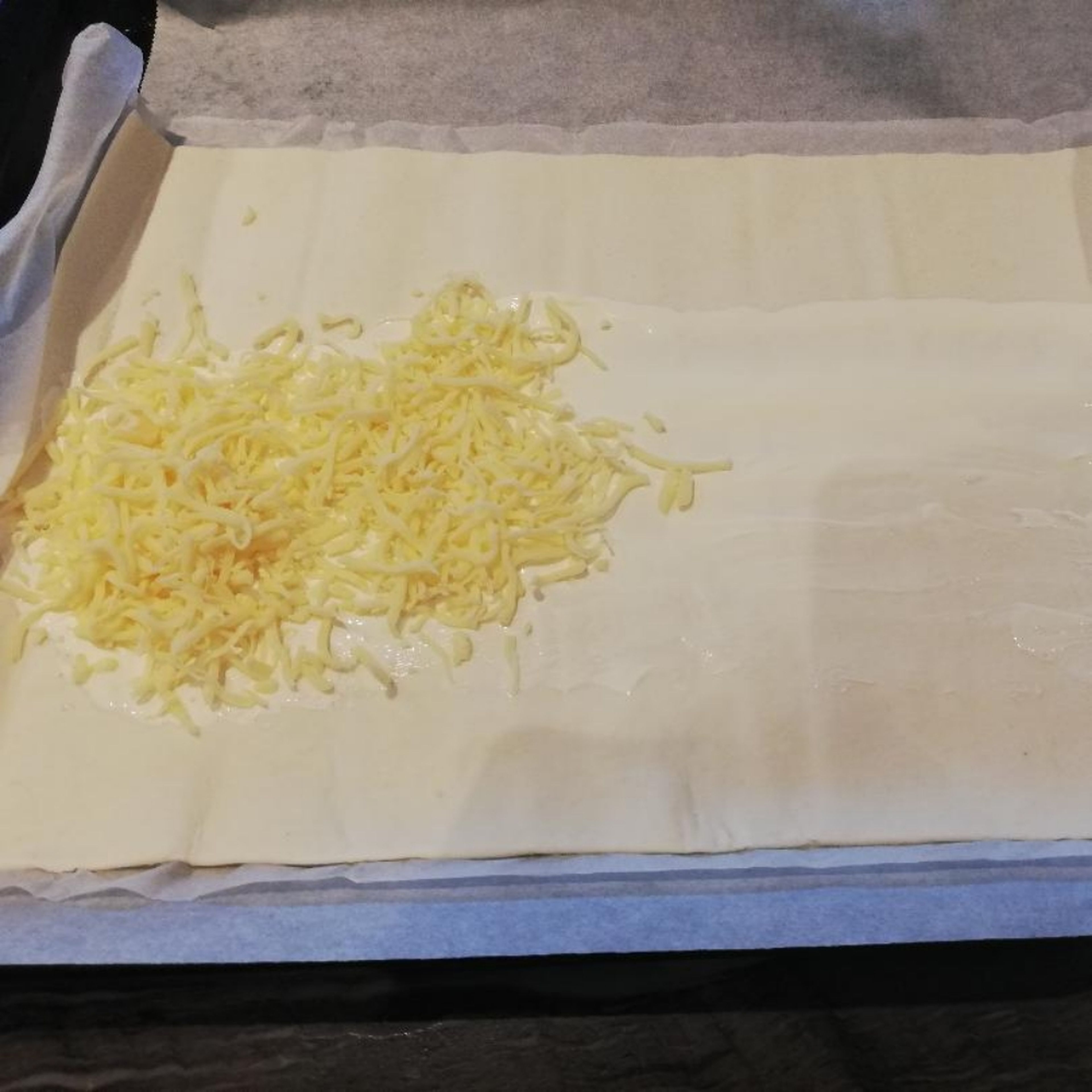 Ofen auf Ober-/Unterhitze 180°Grad stellen. Blätterteig ausrollen. Mit Creme Fraiche bestreichen und Käse bestreuen.