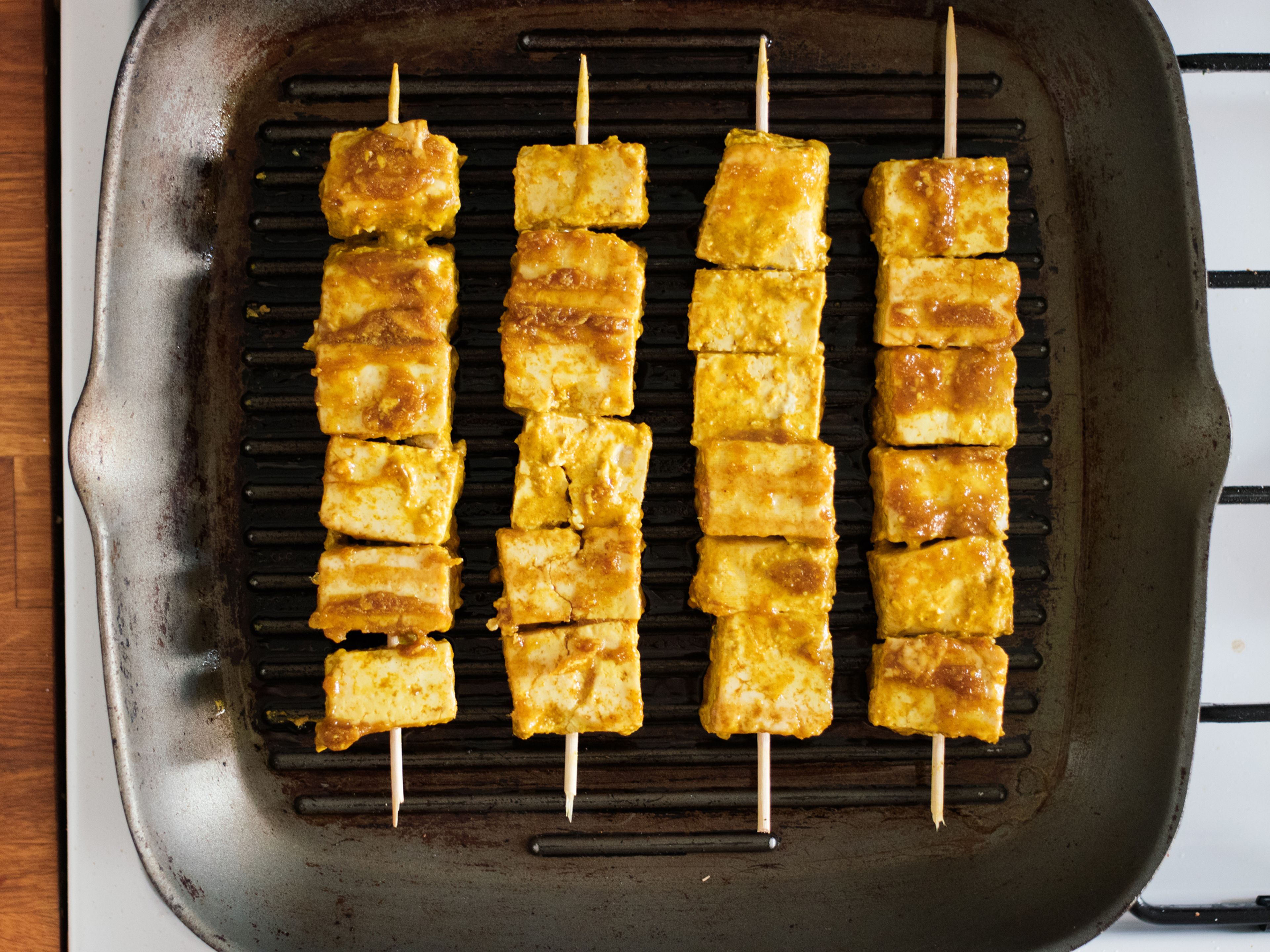 Dust marinated tofu with starch until coated. Thread tofu pieces onto wooden skewers. Heat vegetable oil in a grill pan or a regular frying pan over medium heat. Fry tofu skewers until they are browned on all sides.