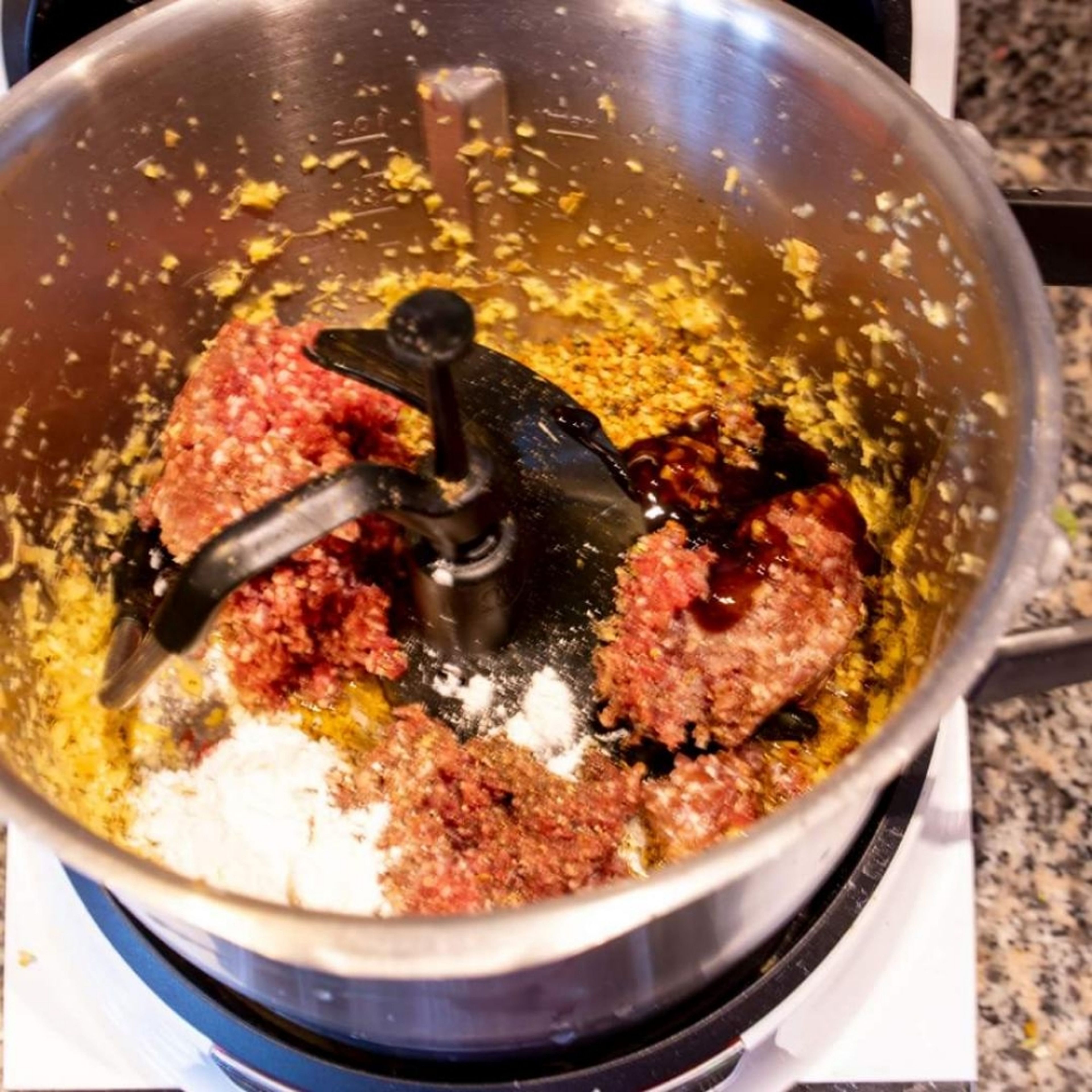 Nun bereiten wir die Fleischfüllung zu. Wir setzen de 3D Rührer ein. Das Hackfleisch mit Salz, gemahlenem Pfeffer, Zucker, heller Sojasoße,Stärkemehl, Austernsoße, einem Spritzer Weißwein, geröstetes Sesamöl, Speisestärke und klein geschnittenen Kräutern zum Ingwer in den Topf des Cookit geben. Dazu ca 50 ml. Wasser. Nun alles gründlich vermengen. Es sollte sich eine homogene Masse bilden, die gut formbar ist. (Universalmesser | Stufe 6 | 2 Minuten).
