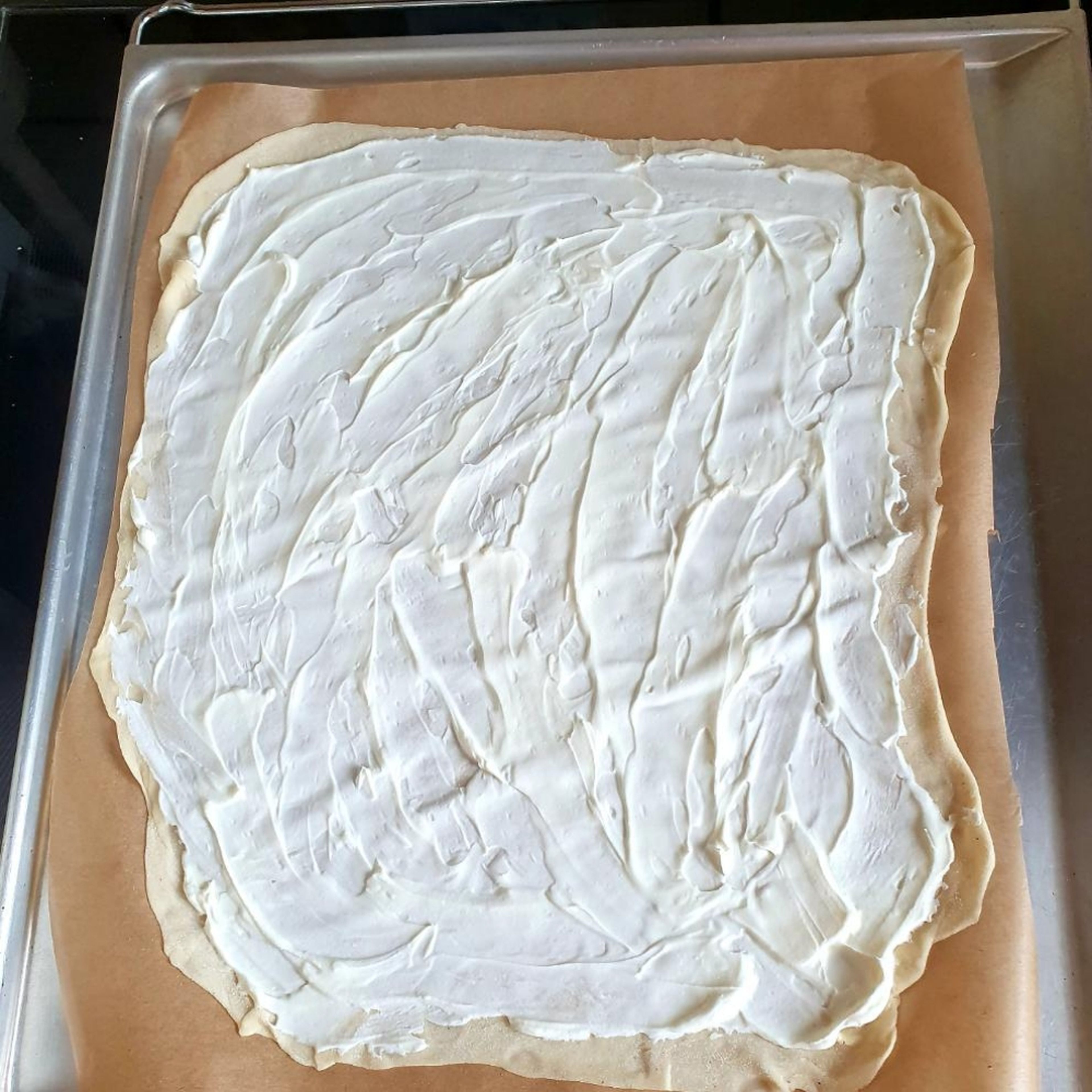Den Teig mit Crème Fraîche bestreichen.