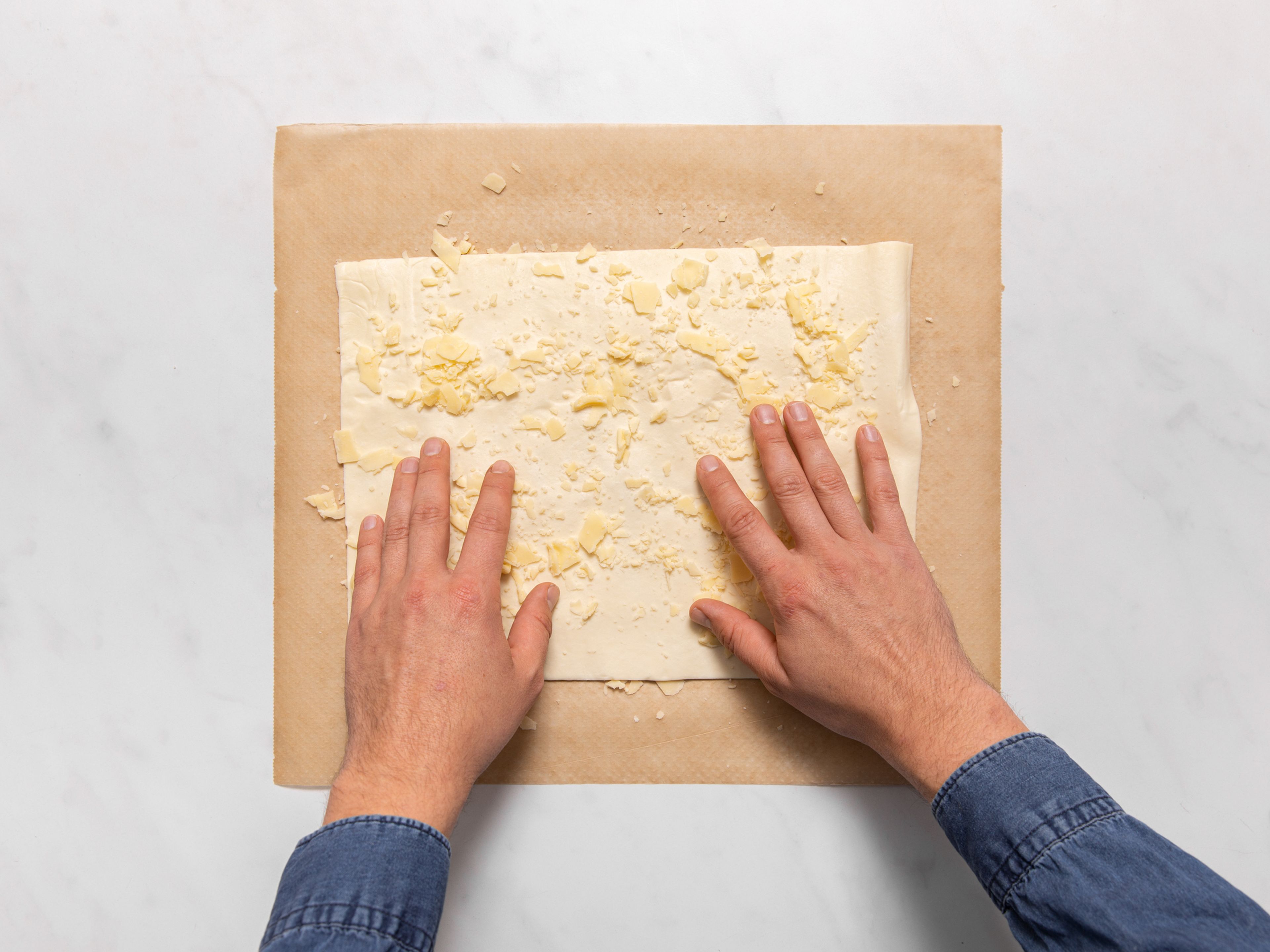 Sprinkle half the cheese onto a work surface and lay a sheet of puff pastry over the top. Sprinkle remaining cheese over the puff pastry. Add a pinch of cayenne pepper over the whole sheet, then roll the pastry into a small log.