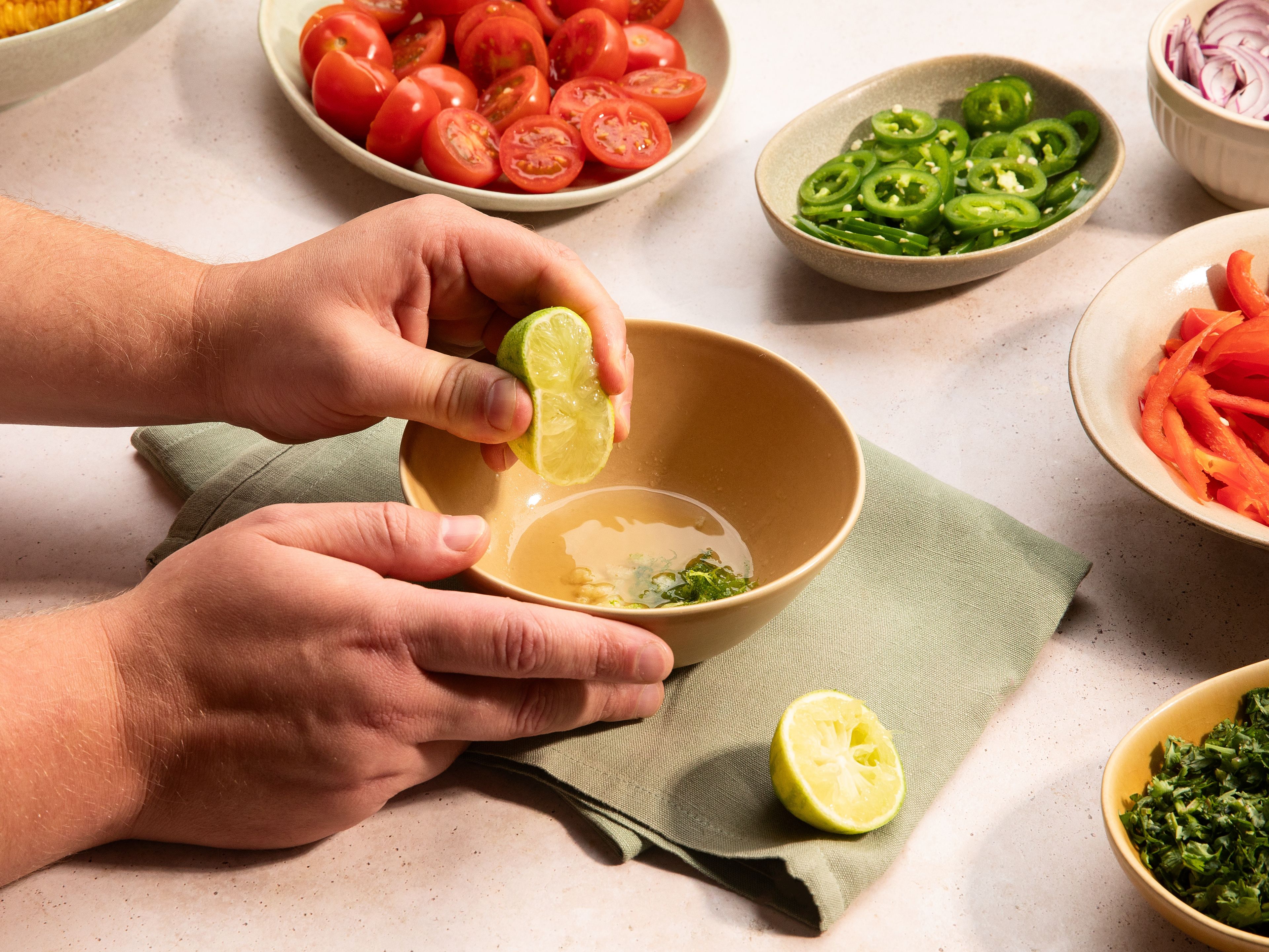 Paprika, Jalapeños und rote Zwiebeln in feine Streifen schneiden. Cocktailtomaten halbieren. Koriander mitsamt der Stiele grob hacken. Für das Dressing Knoblauch schälen und fein in eine kleine Schüssel reiben. Mit Limettenabrieb und -saft, Agavendicksaft, Salz und Pfeffer vermischen. Dann langsam das restliche Olivenöl mit einem Schneebesen einrühren.