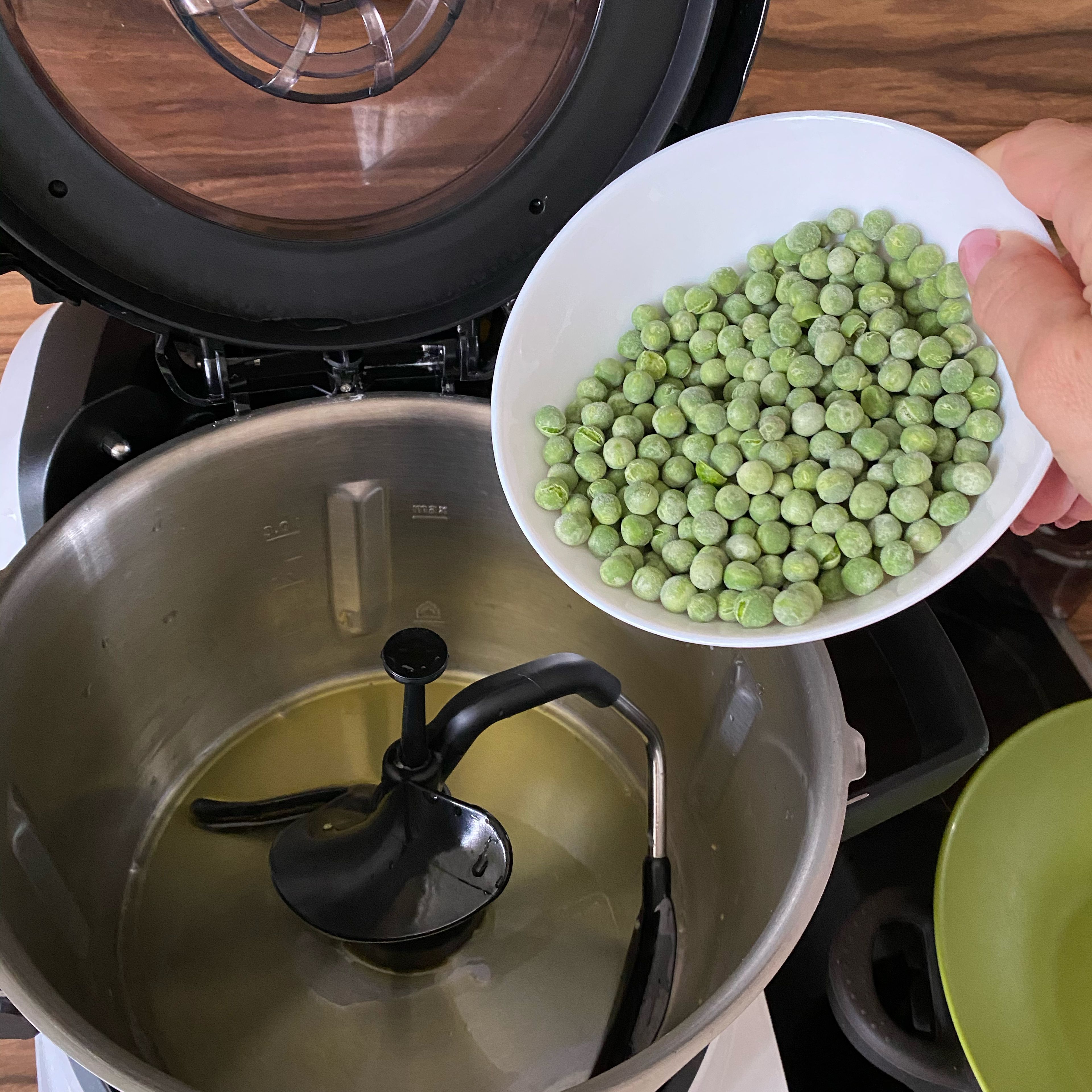 Das Olivenöl einwiegen, Öl bei offenem Deckel erhitzen, 120 Grad/ 2min.
Cookit 3D-Rührer einsetze, Erbsen dazu einwiegen und andünsten,Stufe 4/ 120 Grad/1 min.