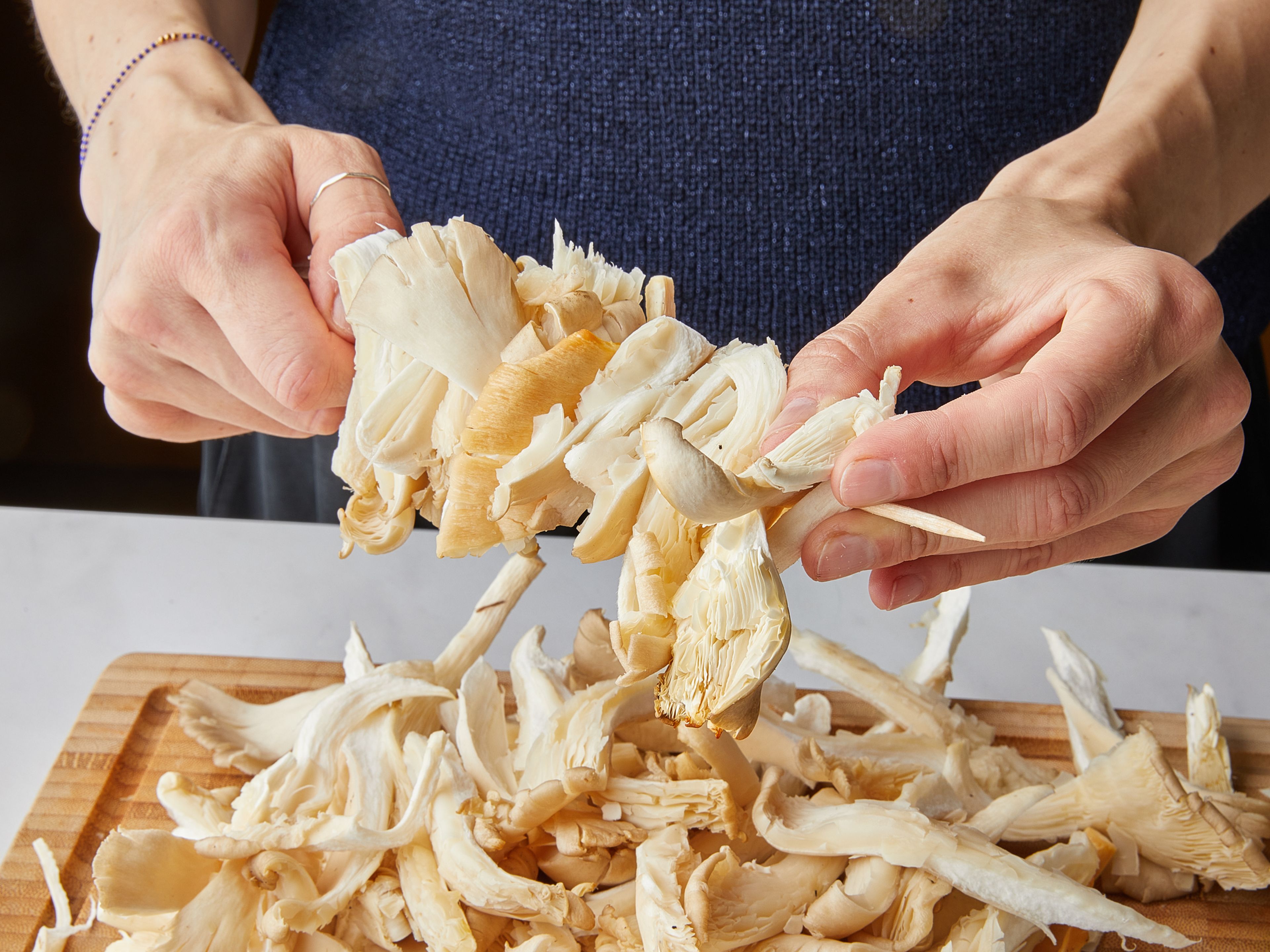 Soak the wooden skewers in warm water for about 30 minutes beforehand. Use your hands to tear the oyster mushrooms into even strips. Then place the mushroom strips closely but evenly spaced on the wooden skewers. This makes about 6-8 skewers.